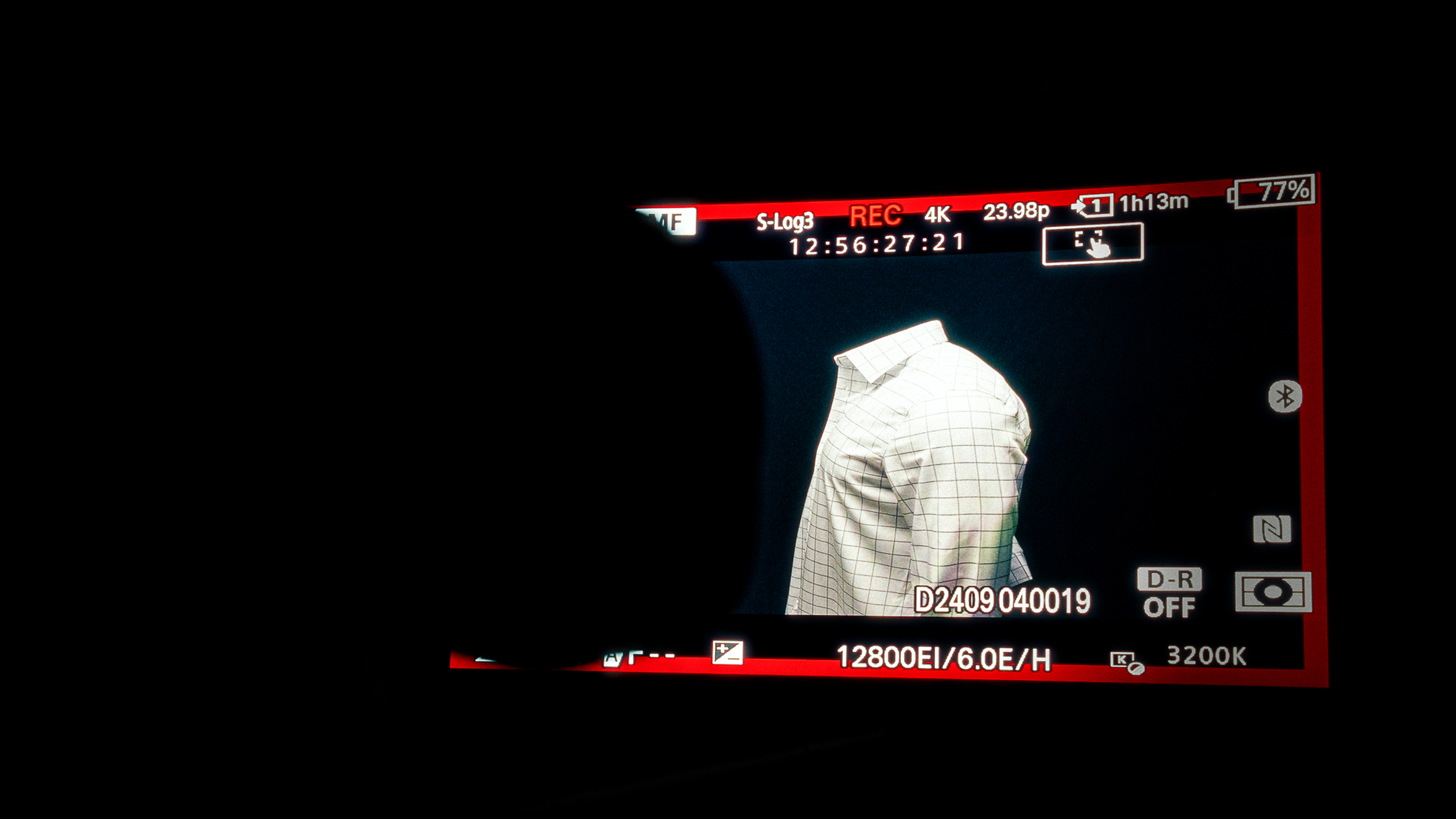 Camera viewfinder displaying a checkered shirt on a mannequin during a photo shoot or recording session