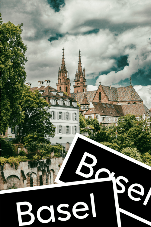 Historische Gebäude und zwei Türme der Basler Münster in Basel, Schweiz, unter einem bewölkten Himmel.