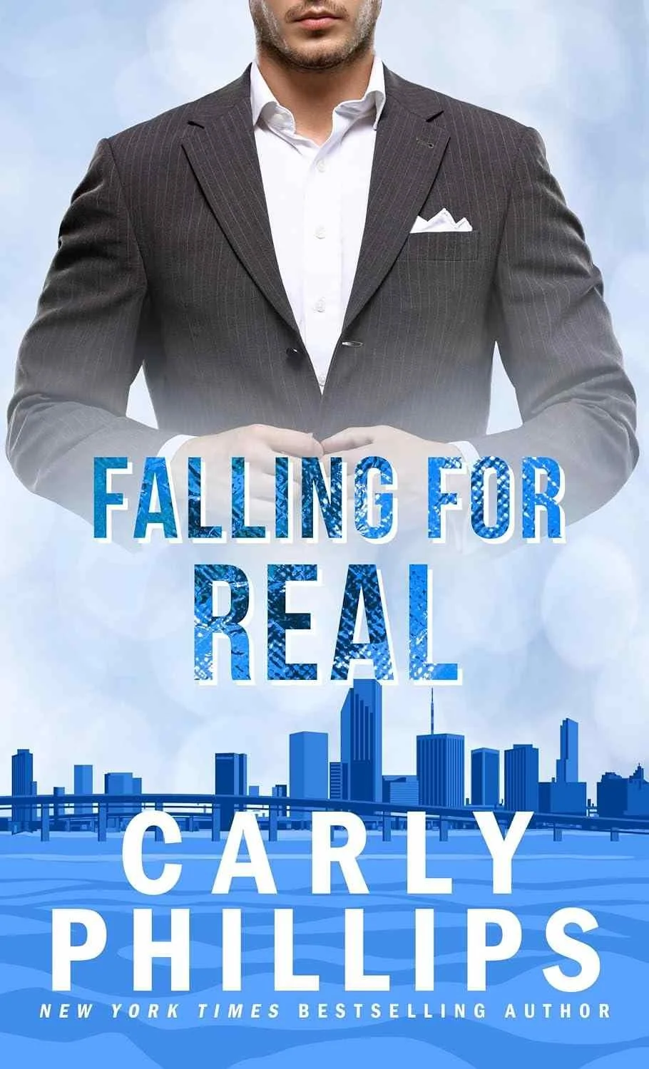 Book cover graphic for Falling for Real by Carly Phillips featuring business man in a suit over city skyline
