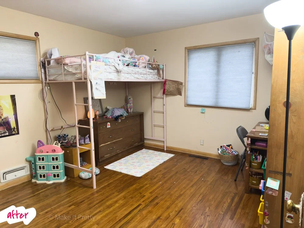 A child's bedroom with a loft bed, dresser, and desk. The room has hardwood floors, two windows with blinds, and children's toys and belongings.