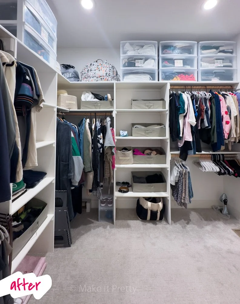 Organized walk-in closet with white shelving units, hanging clothing, clear plastic storage bins on top, and various folded clothes and accessories.