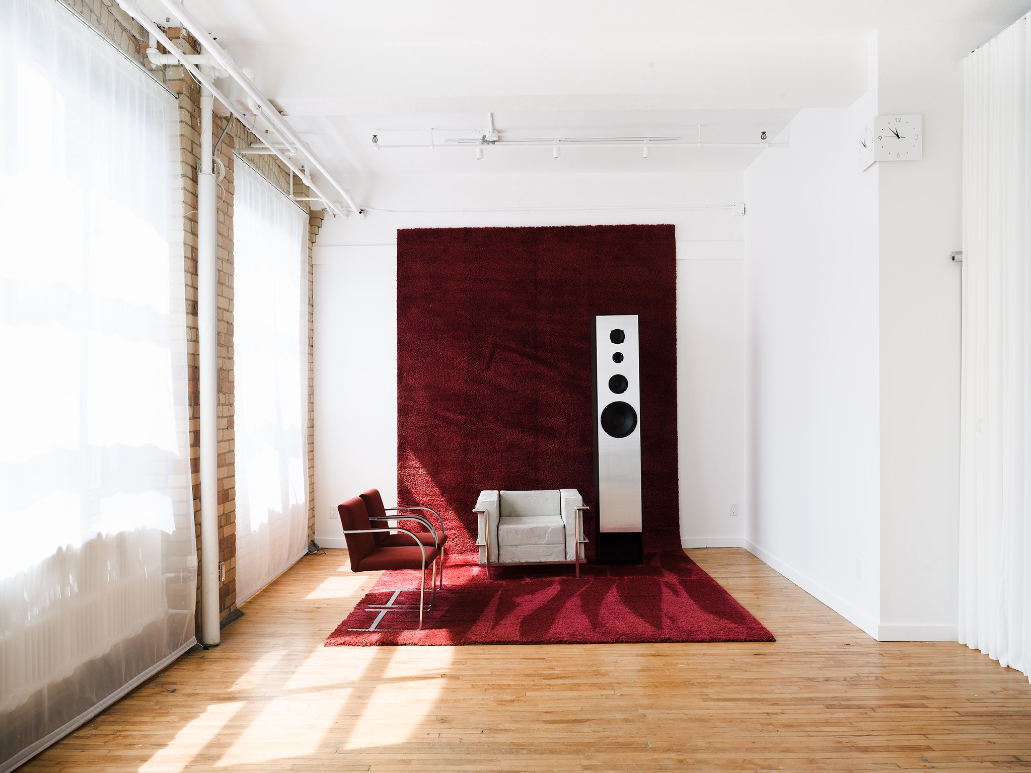 Modern lounge area at On2 Studio in downtown Toronto featuring red shag carpet, Bauhaus-inspired seating, and natural light from large loft windows.