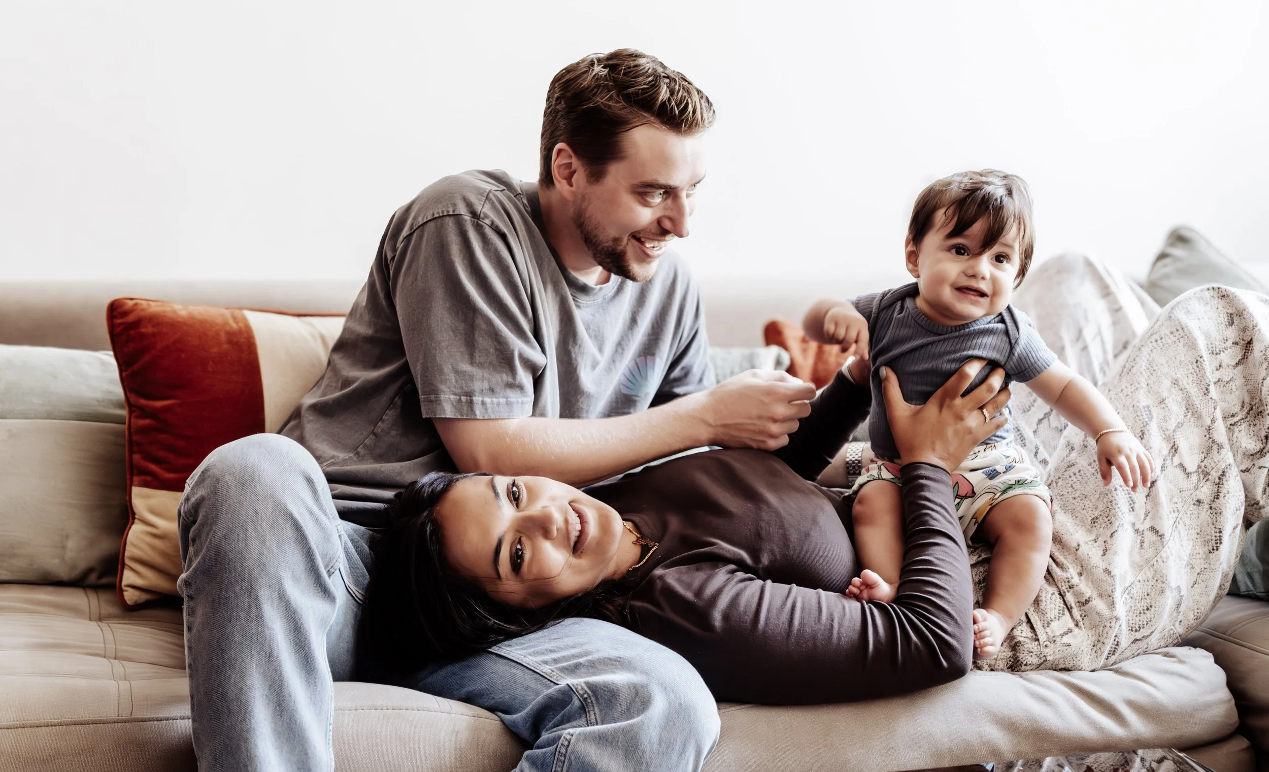 Een man en een vrouw houden samen een slapende baby in hun armen.