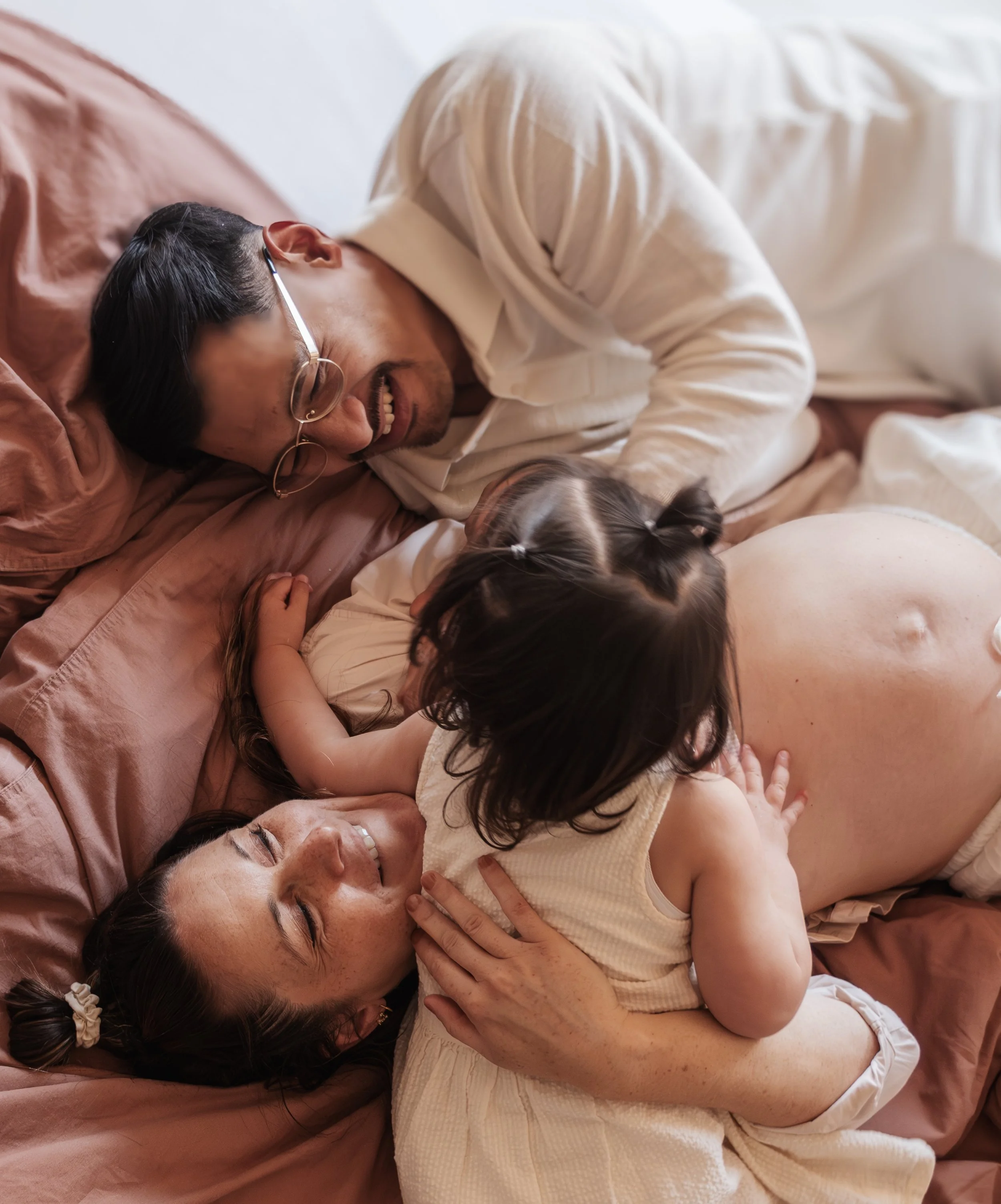 Een man en een vrouw houden samen een slapende baby in hun armen.