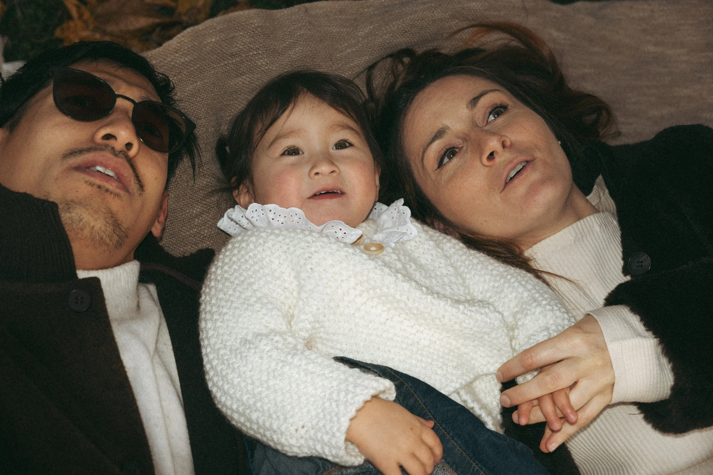 Een man en een vrouw houden samen een slapende baby in hun armen.