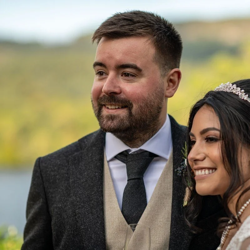 Andrew Mackay, A Maritime professional, dressed in wedding attire, outdoors with blurred trees and sky in the background.