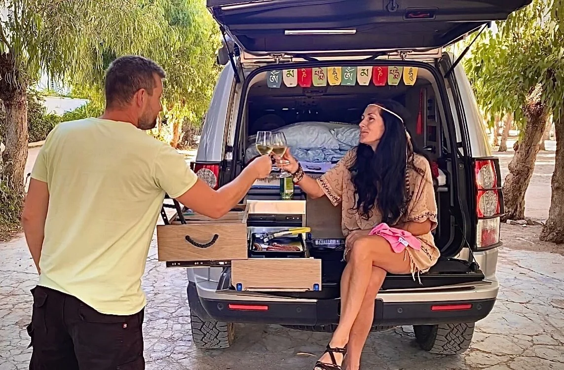 Mirinda and Lucas drinking wine on the back of their self converted Discovery 4 oveland