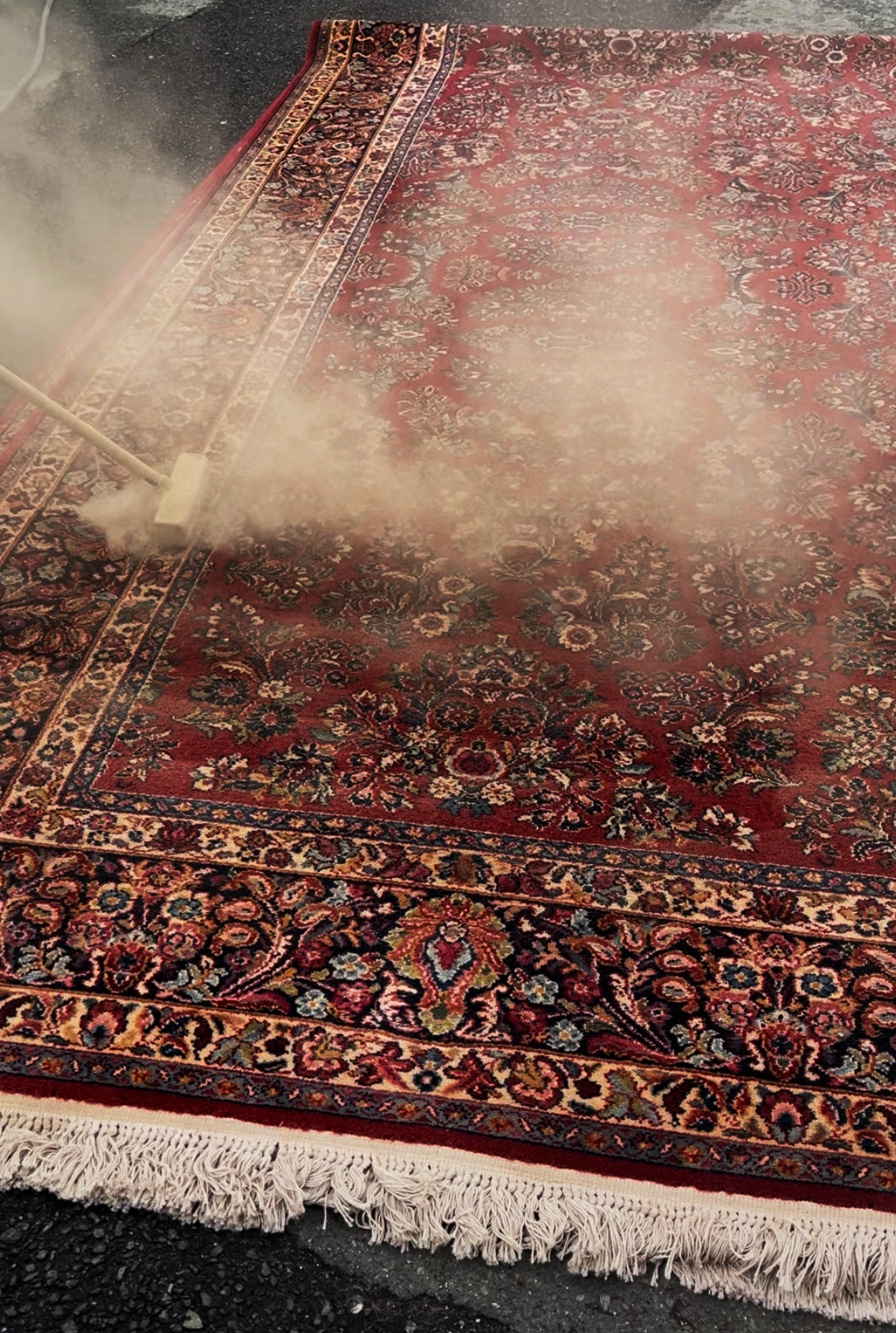 Photo of a large oriental rug going through the first step of the cleaning process: dusting.