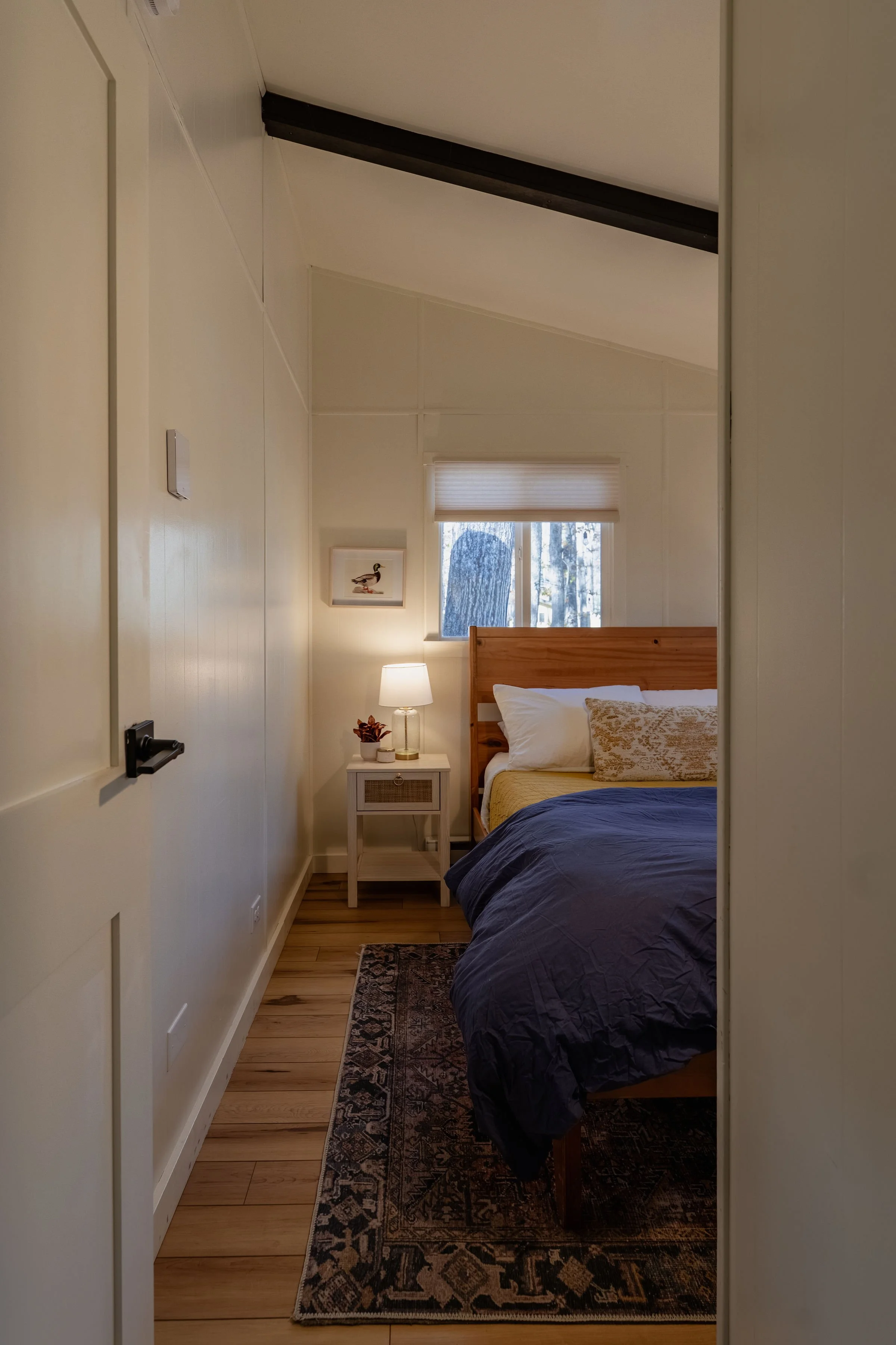 This cozy bedroom features a queen bed two nightstands with lamps and a drawer, multiple charging outlets and framed bird artwork on the walls.