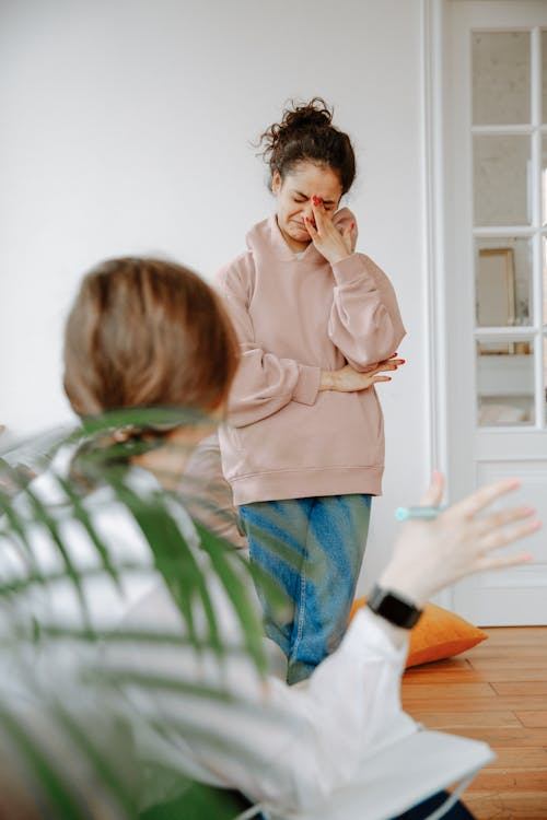 A woman appears upset and is crying, while a therapist or counselor listens and takes notes during a session.