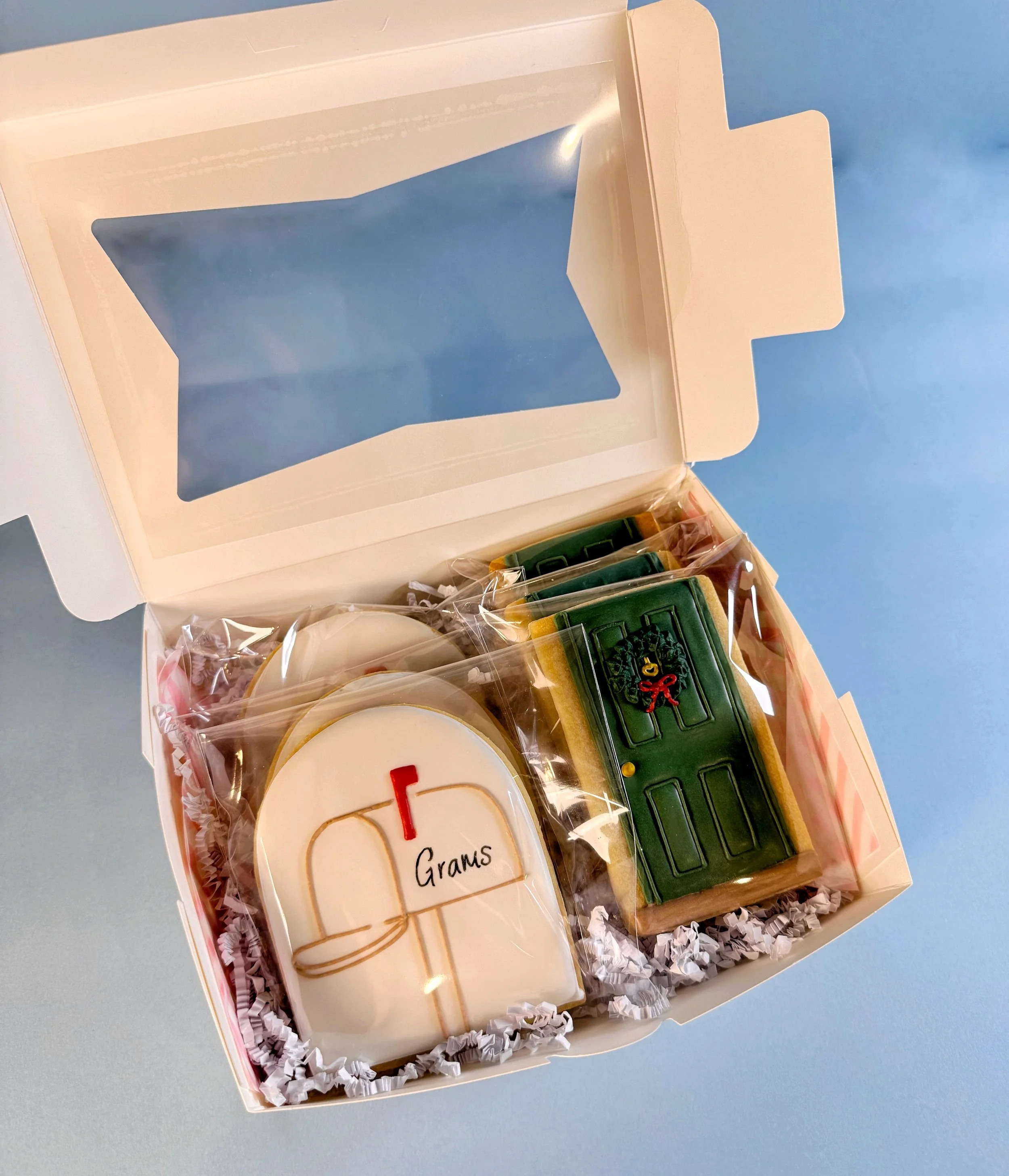 Custom gift Box of Christmas-themed decorated cookies, including a mailbox, and a decorated door with a wreath.