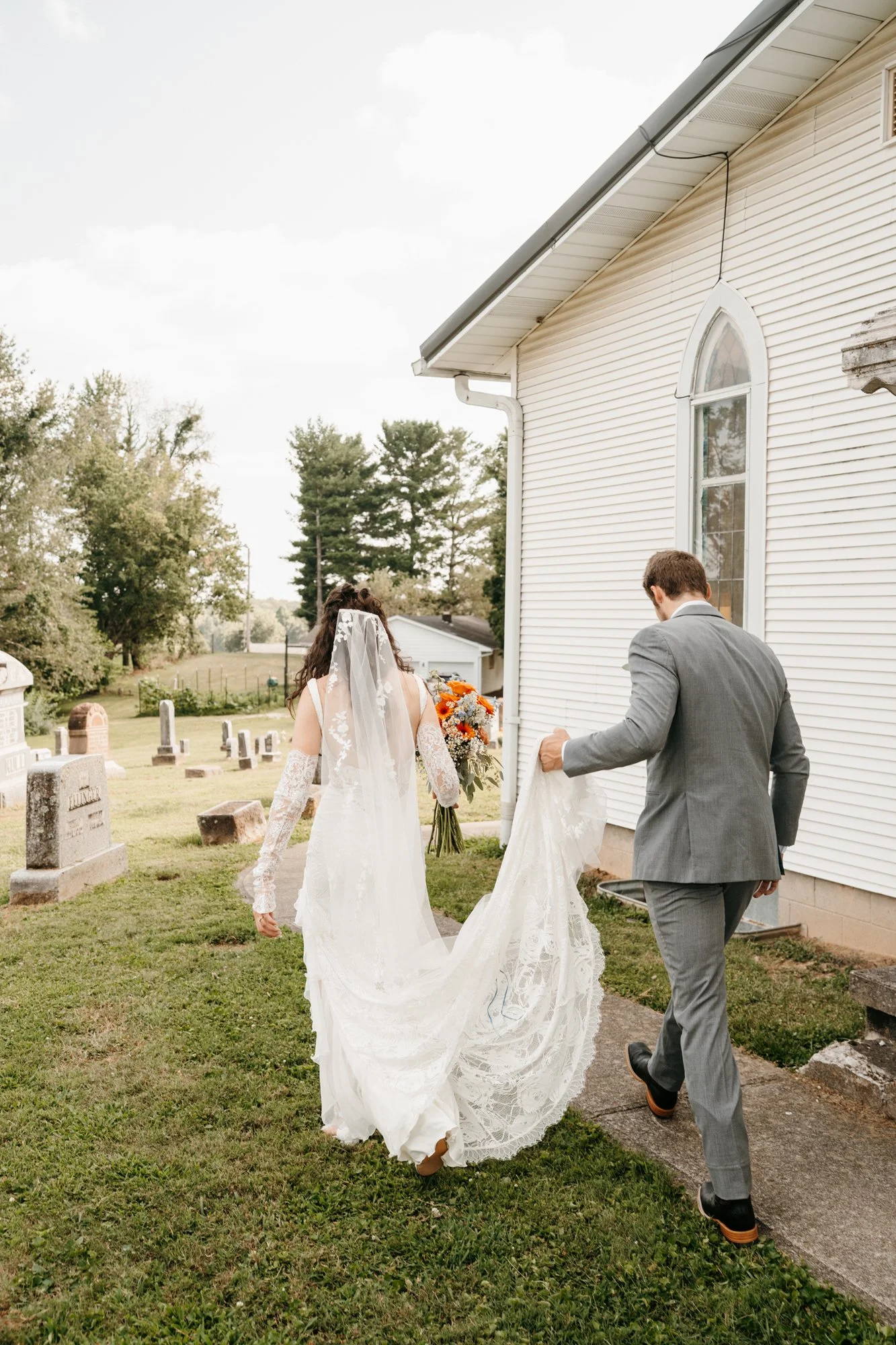 A bride and groom walking away from a church, with the bride holding a bouquet of flowers, as they leave a wedding ceremony.