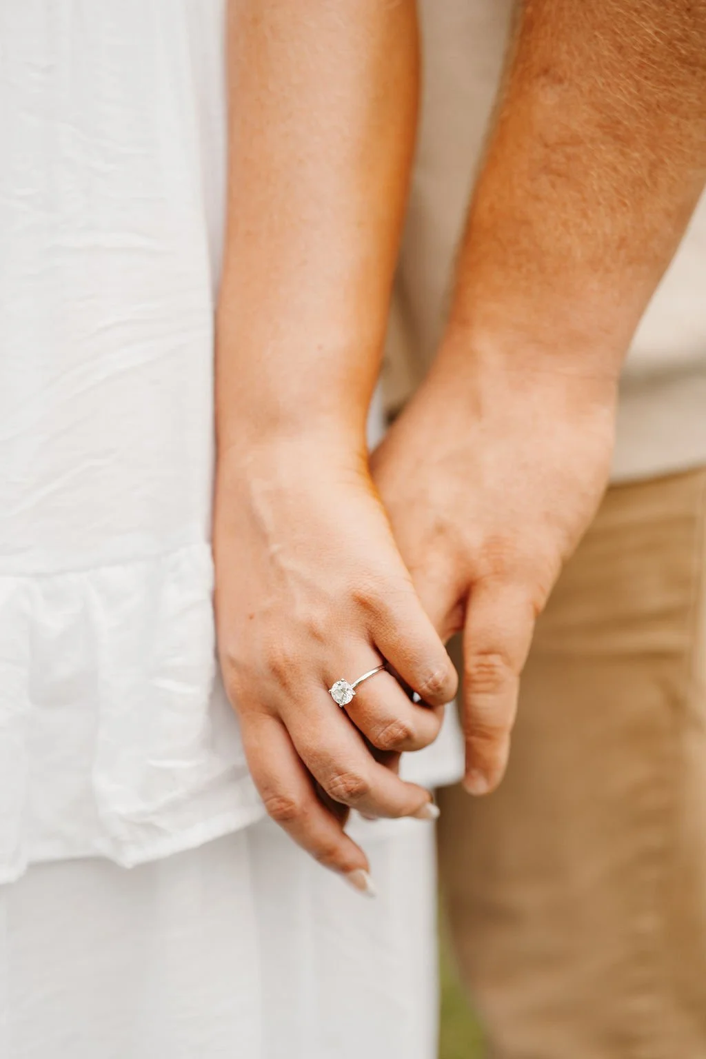 Close-up of two hands holding each other, with one hand wearing a ring with a diamond.