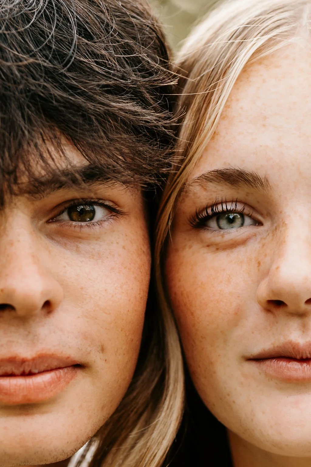 Close-up of two young women with different hair colors and eye colors, smiling softly.