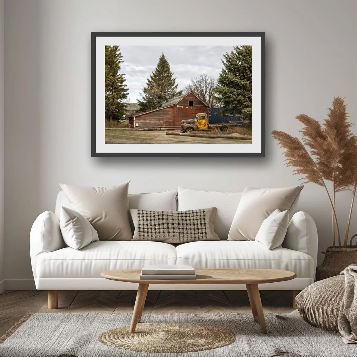 Living room with a white sofa, pillows, a wooden coffee table, a framed outdoor picture on the wall, and decorative plants.