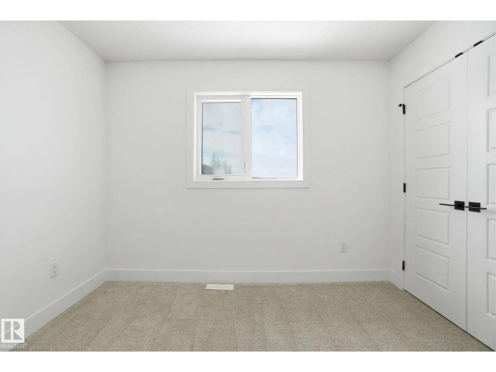 Empty room with white walls, a window, and a closet with white doors.
