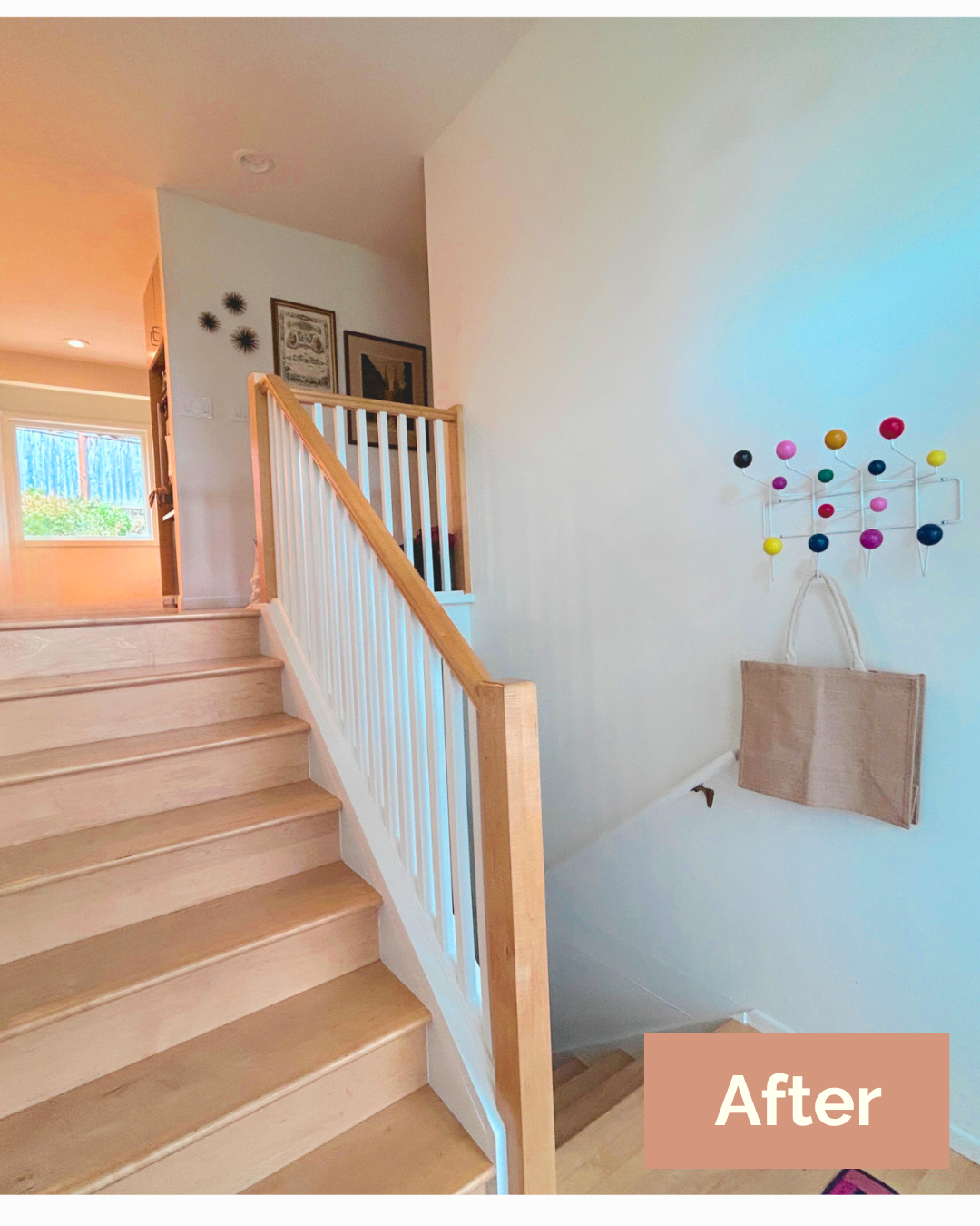 a clean entryway with stairs and a bag hanging on a coat rack