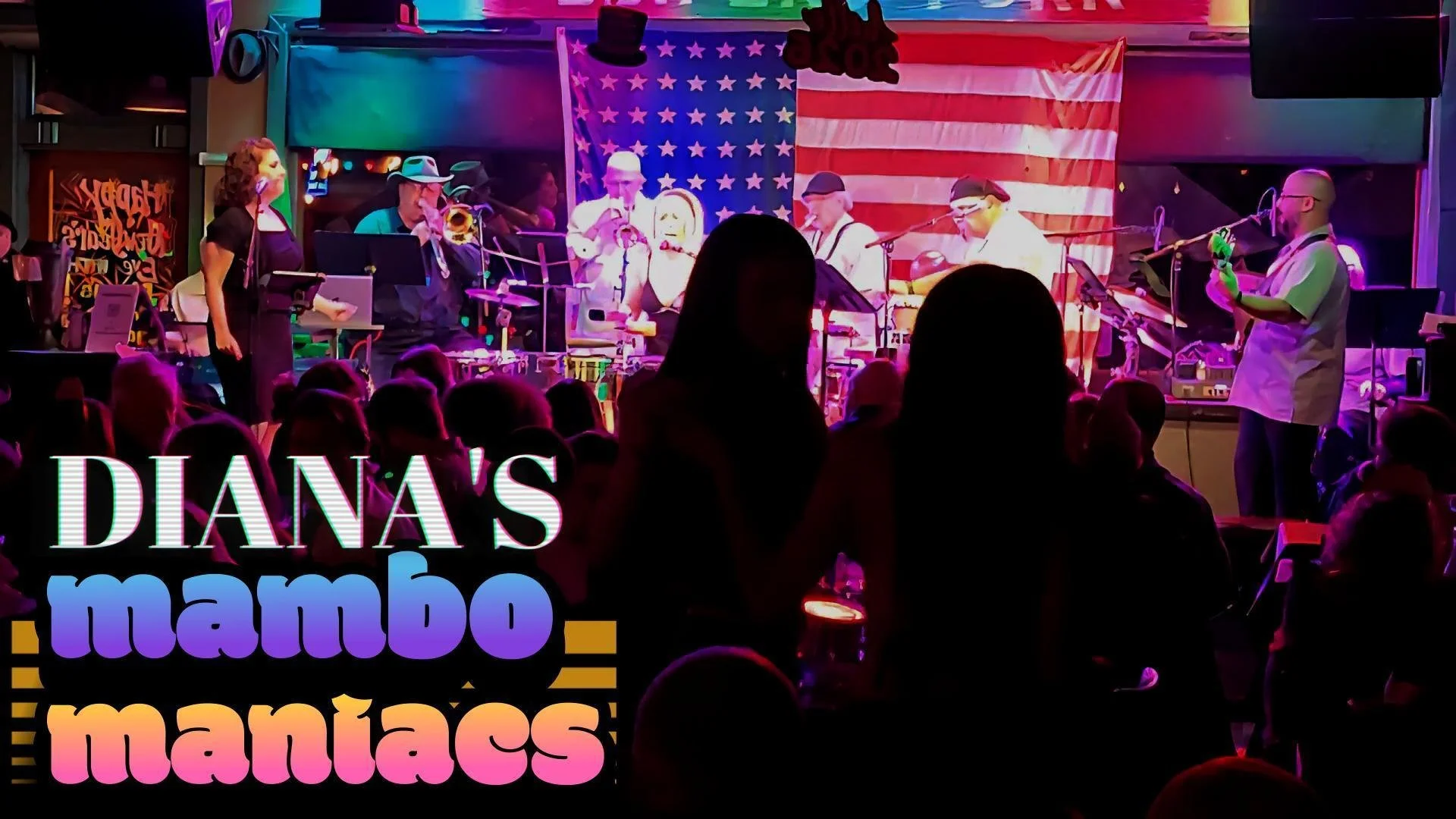 A stage with a jazz band performing, with American flags and a neon sign saying "Yoyosh" in the background. Audience silhouettes visible in the foreground and colorful promotional text for "Diana's mambo maniac" in the lower left corner.
