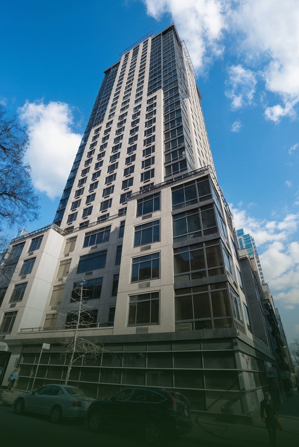A skyscraper against a blue sky with a few scattered clouds.