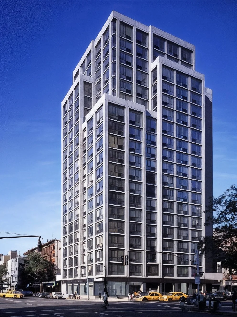 A highrise apartment building sits against a clear blue sky