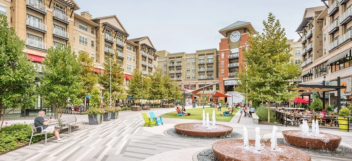 Fountains sit in a plaza in front of restaurants and multifamily apartment buildings