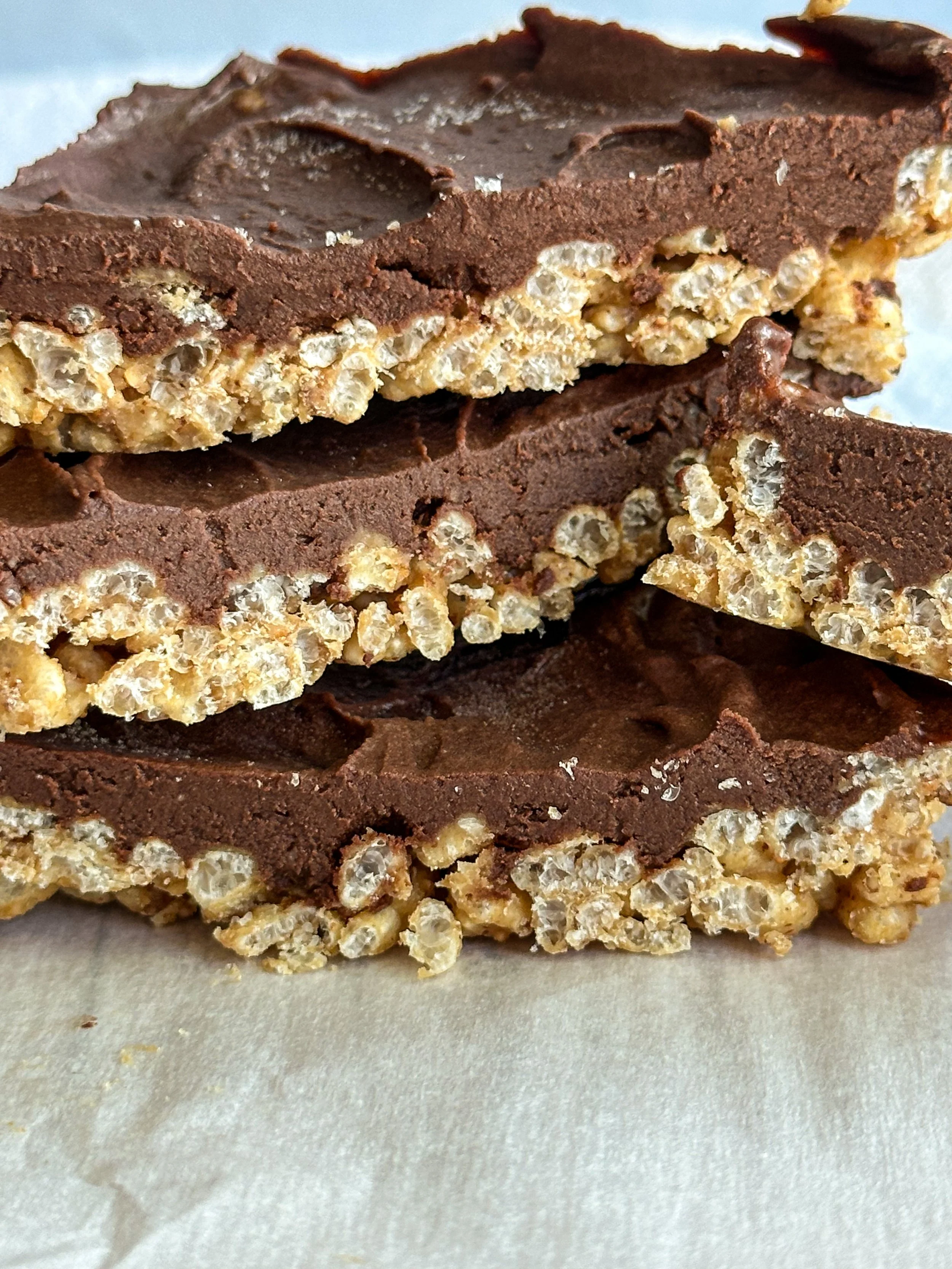 Close-up of layered chocolate crispie square showing gooey fudge topping