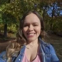 Young woman smiling outdoors in a park with trees in the background