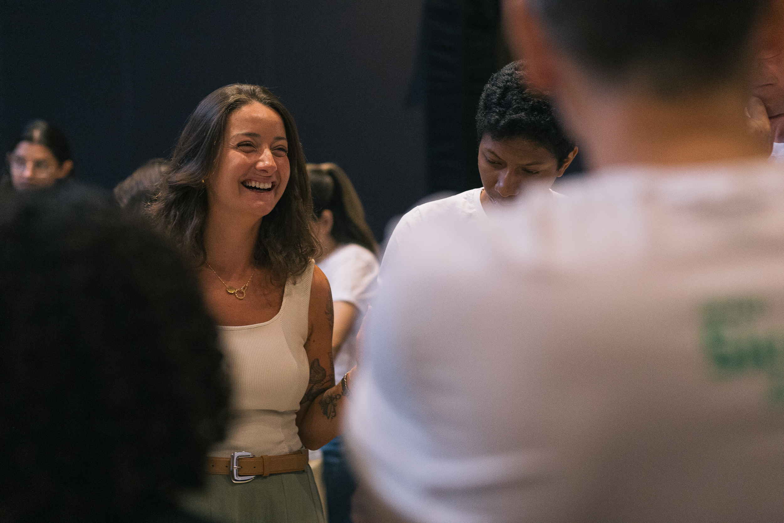 Mulher sorridente conversando com um grupo de pessoas em um ambiente social.