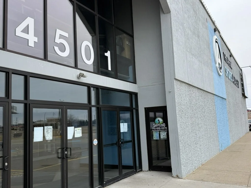 The exterior of a building with large glass windows displaying the numbers 4501 and a sign for Siouxland with a phone number and logo.