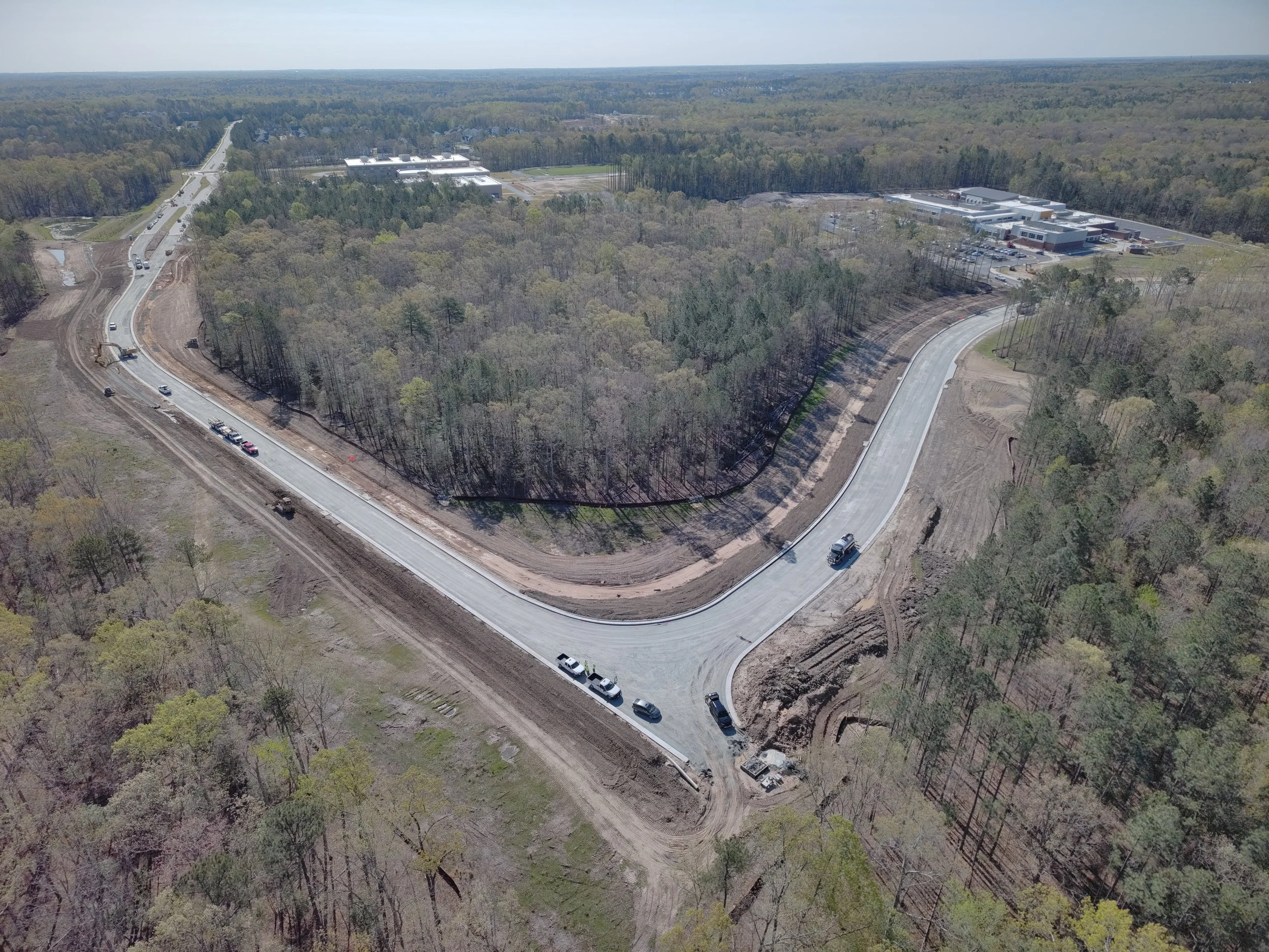 Curb and asphalt installation begins. Bridge work continues with girder erection. Pipe work continues.
