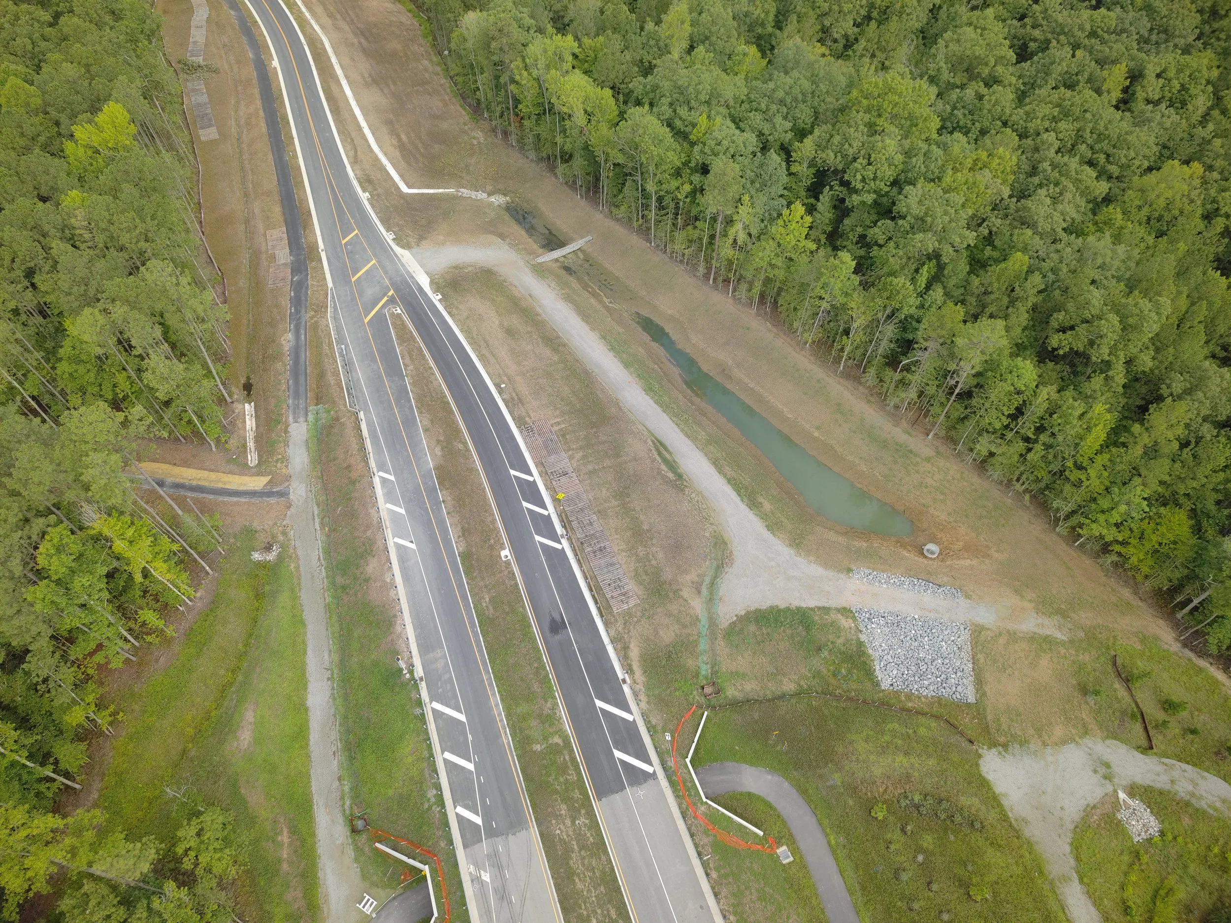 Roadway work continues with curb/underdrain installation and paving to follow. Work on the bridge reaches final stages with sidewalk and railing installation.