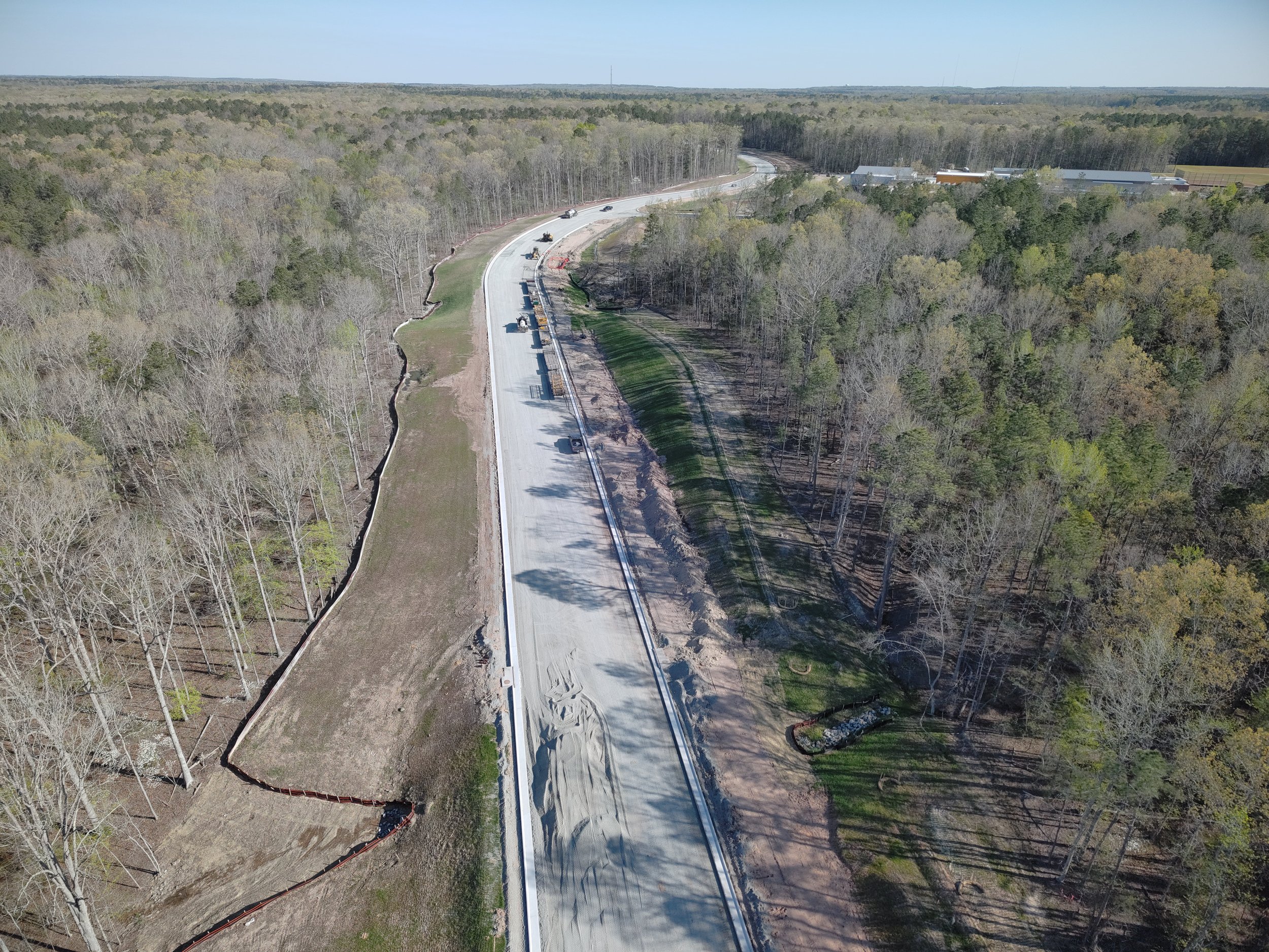 Curb and asphalt installation begins. Bridge work continues with girder erection. Pipe work continues.