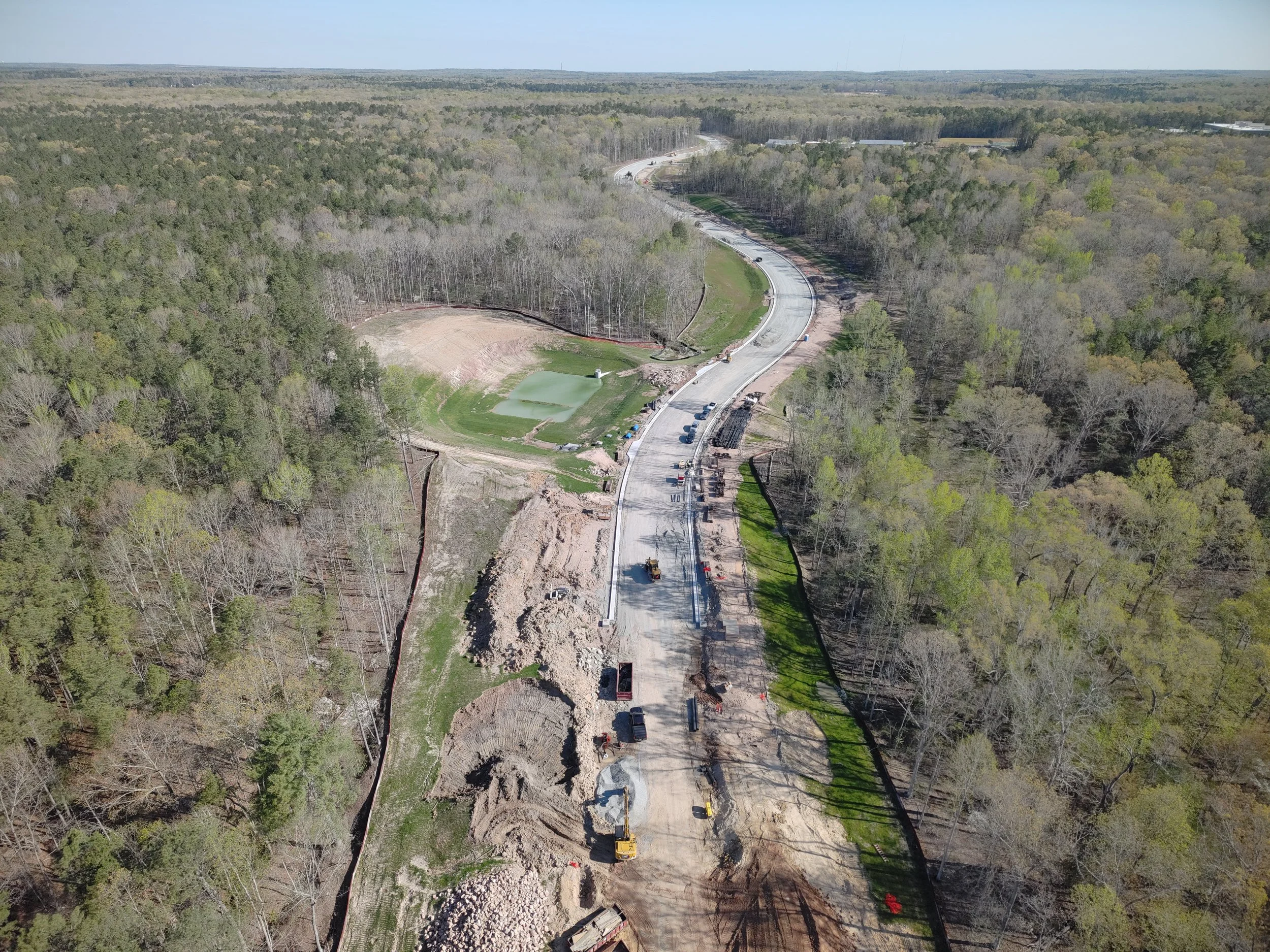 Curb and asphalt installation begins. Bridge work continues with girder erection. Pipe work continues.