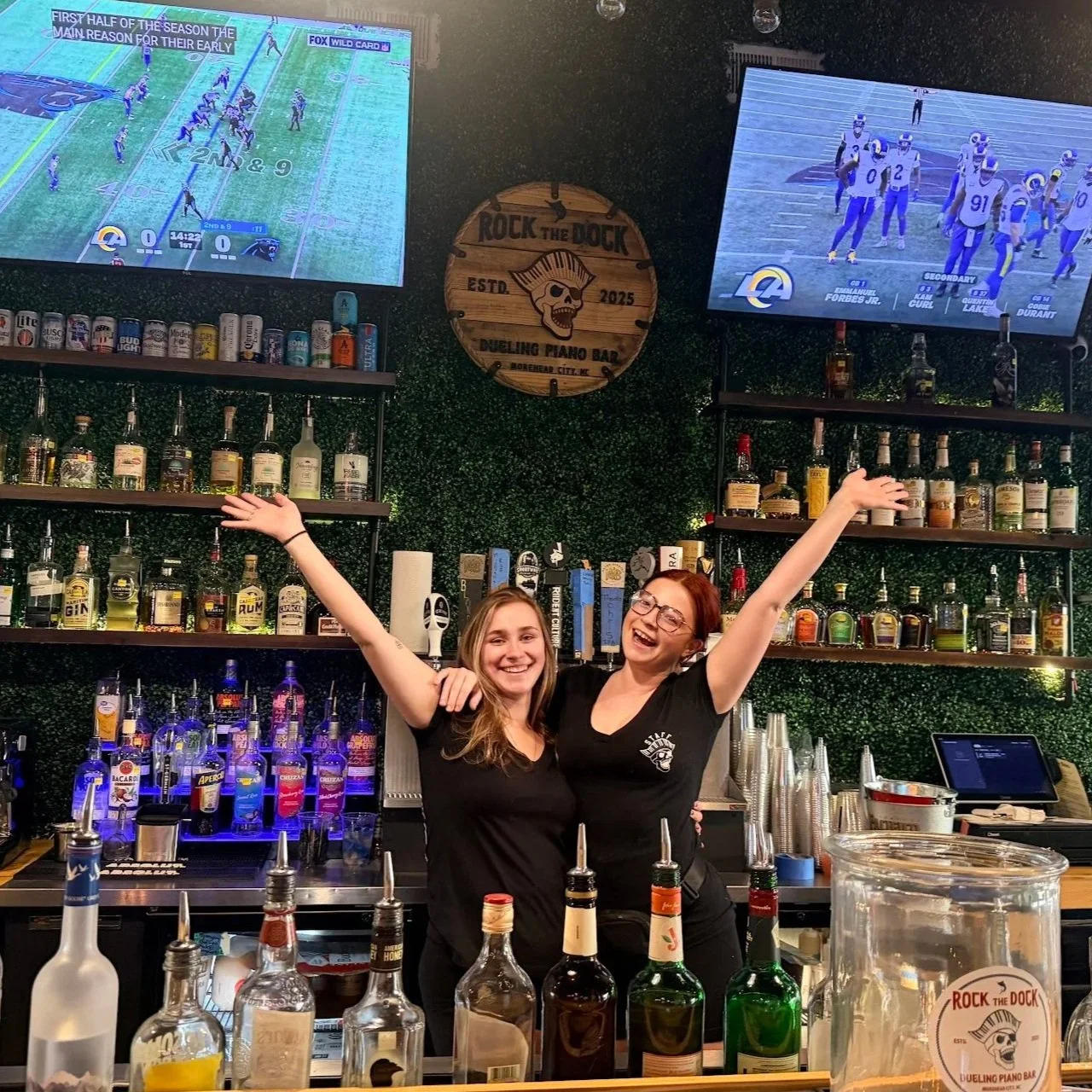 Rock the Dock bartenders smiling behind the bar at the dueling piano venue in Morehead City NC