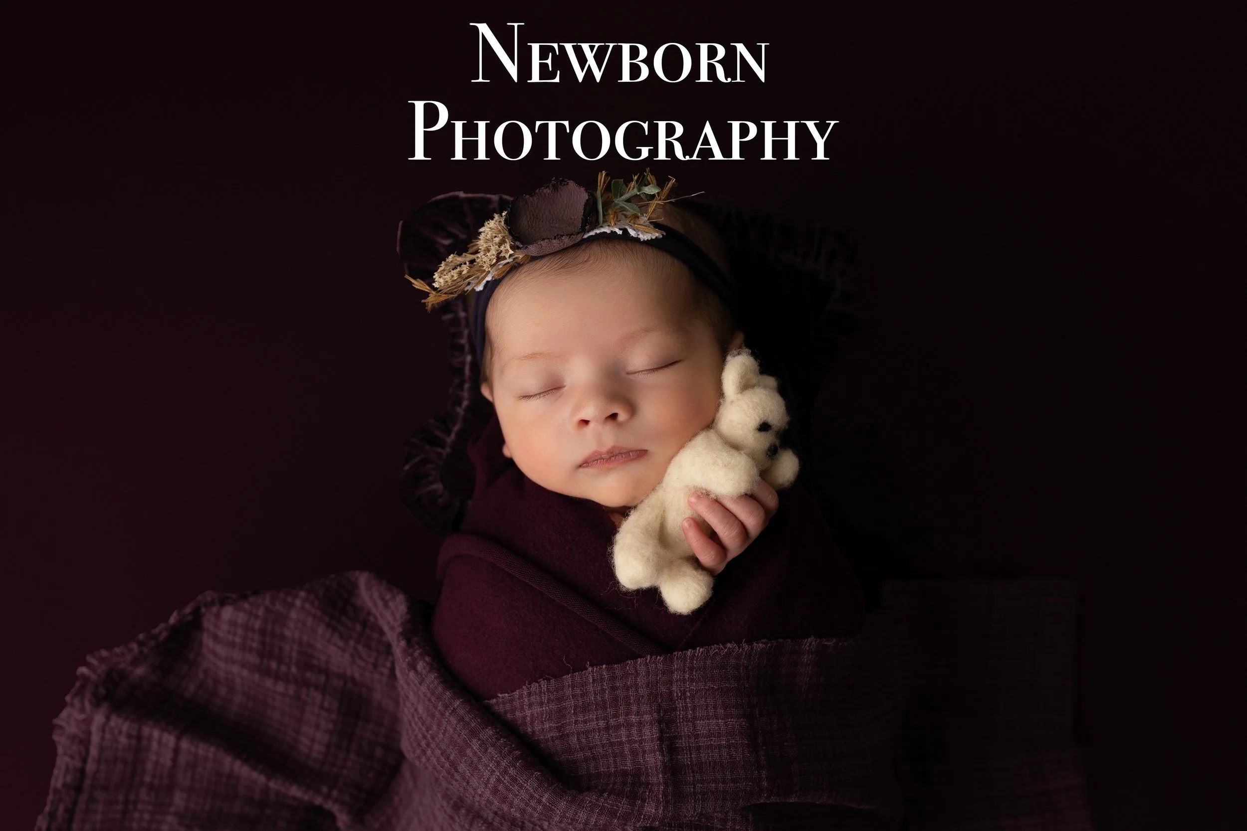 A sleeping newborn baby wrapped in a dark purple blanket, holding a small white stuffed bear, with a dark background and the text "Newborn Photography" above.Louisville Kentucky Newborn Photographer