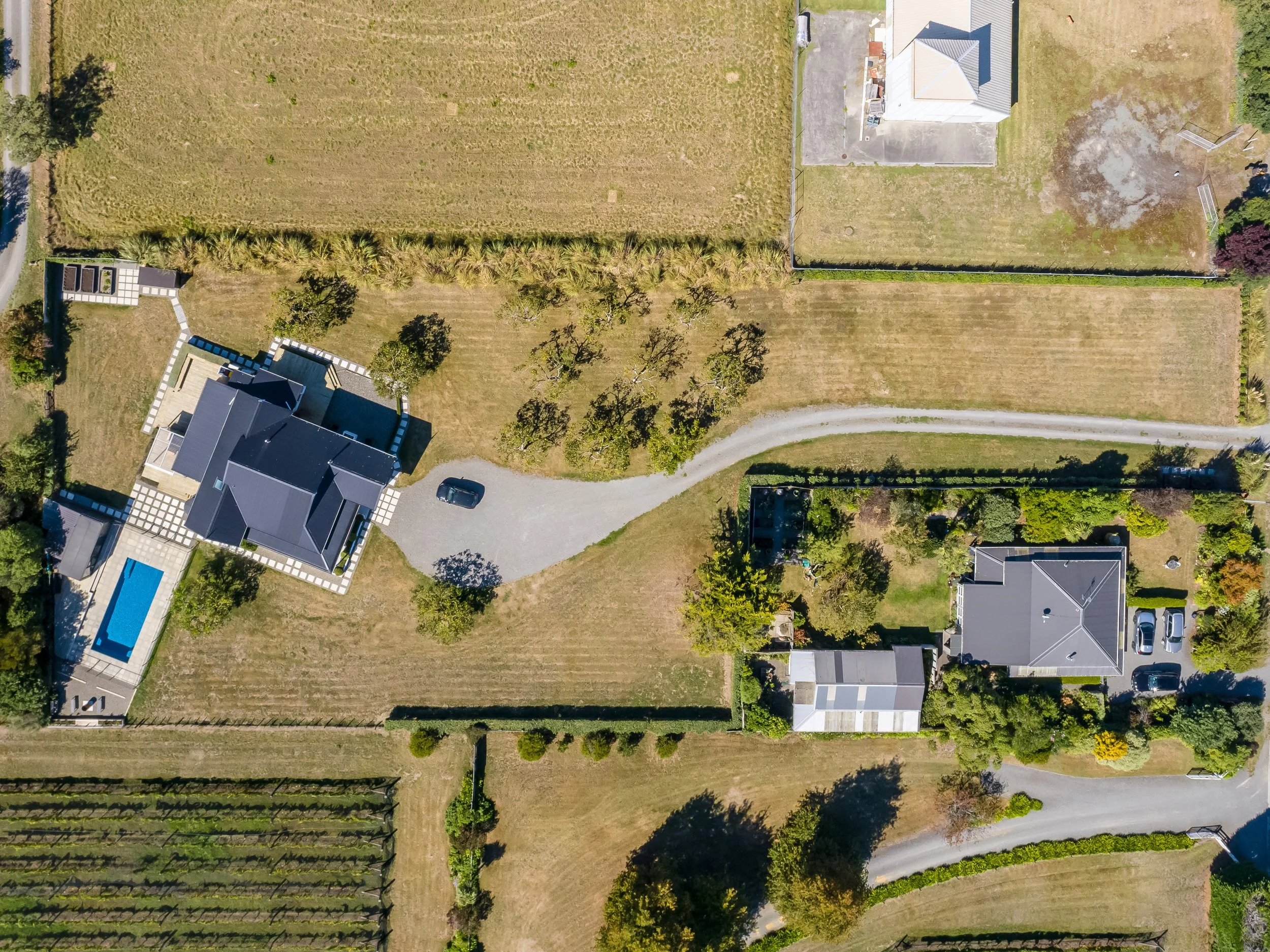 Aerial view of a large country section in which a large white villa and swimming pool are set at the end of a curving driveway that winds between large lawns and rows of trees. Great for weekend stays, small weddings and post wedding events.

