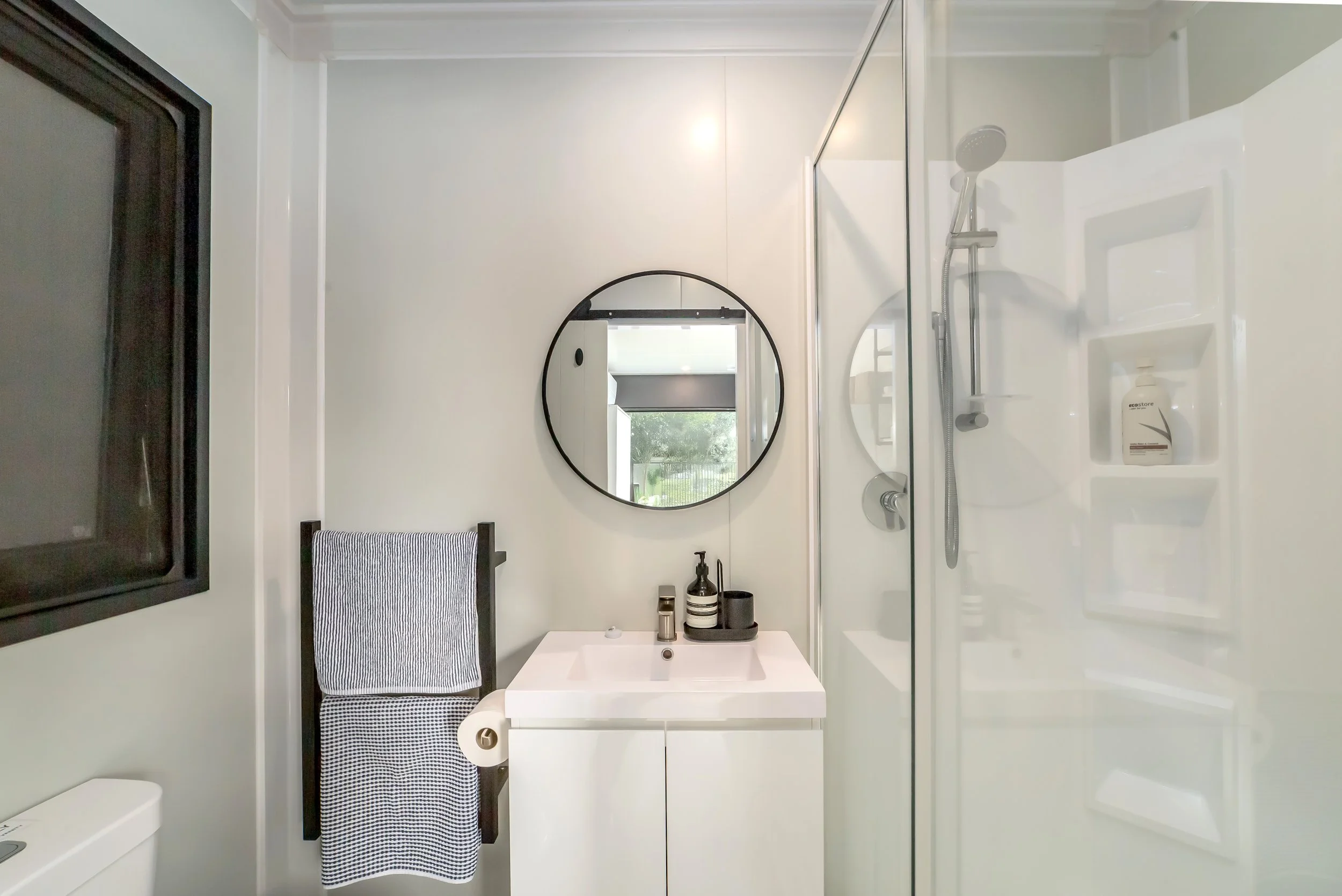 The pool house bathroom with a white vanity, round mirror and shower. Great for weekend stays, group gatherings, celebrations and holidays.
