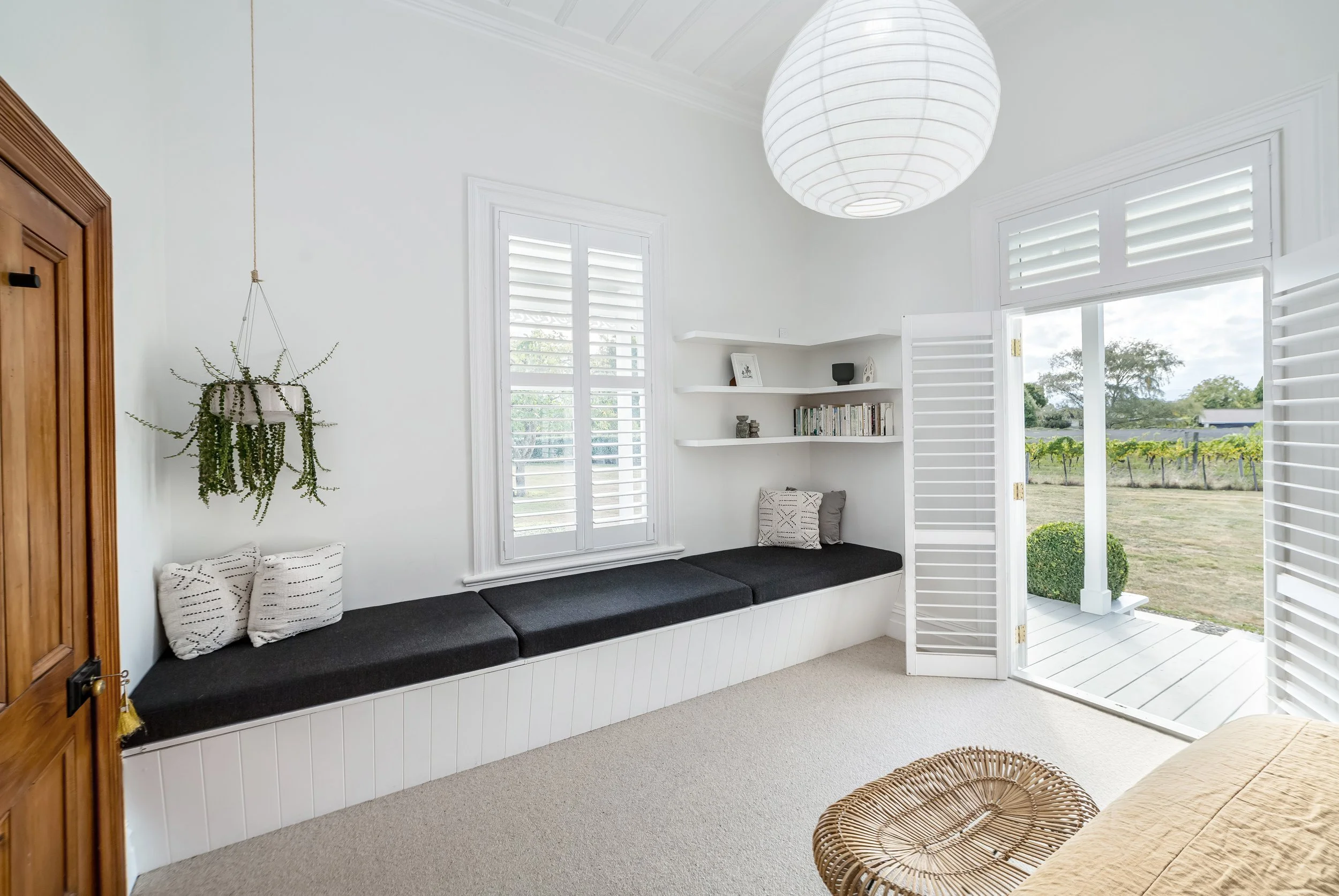 A modern white bedroom with ensuite. Clean simple lines with mustard and black accent colours and designer lamps. French doors open to a porch. Great for weekend stays, small weddings, post wedding events, group gatherings, celebrations and holidays.