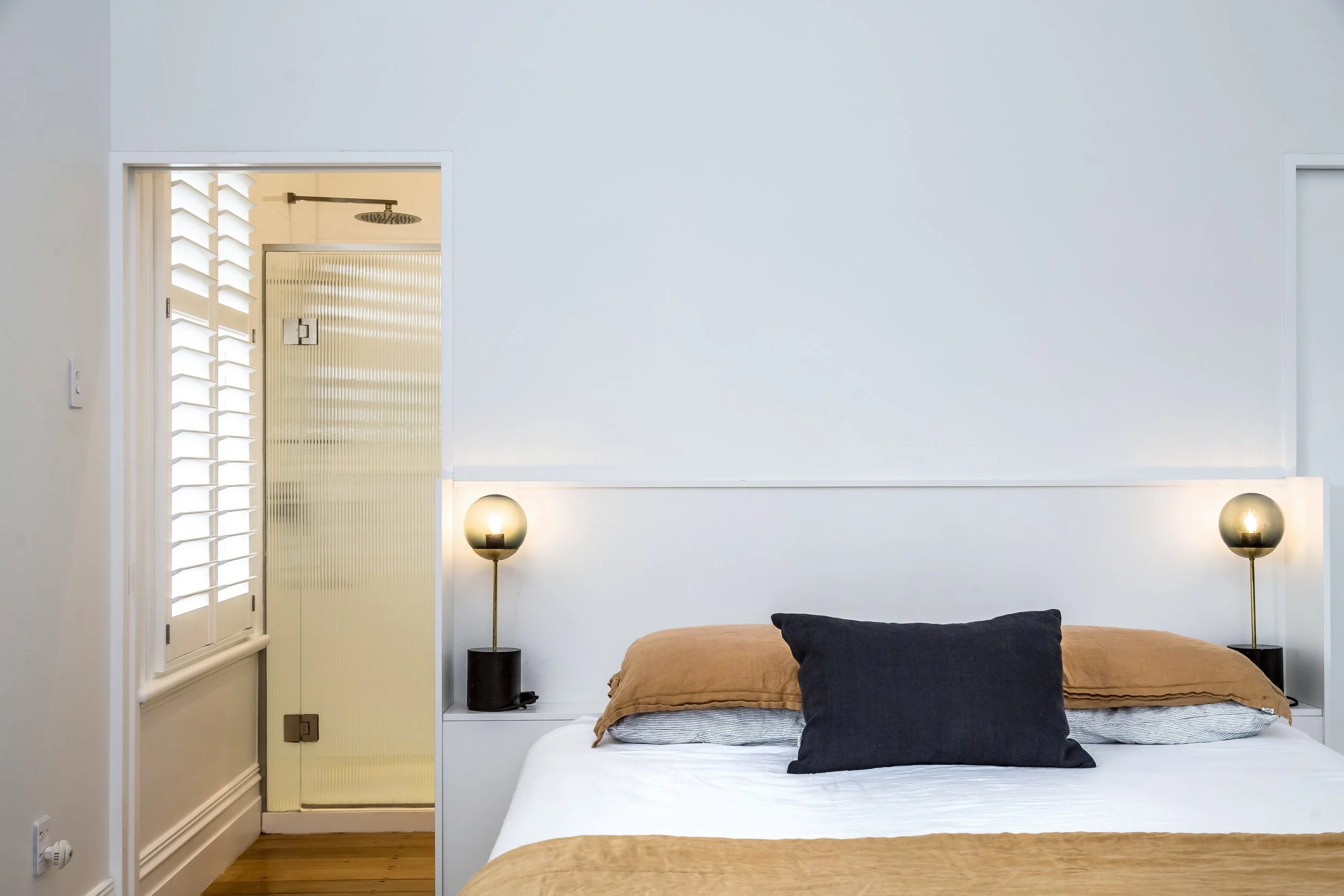 A modern white bedroom with ensuite. Clean simple lines with mustard and black accent colours and designer lamps. Great for weekend stays, small weddings, post wedding events, group gatherings, celebrations and holidays.