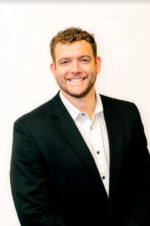 Man in black suit with no tie curly hair. Dalton Pierce-Speer.