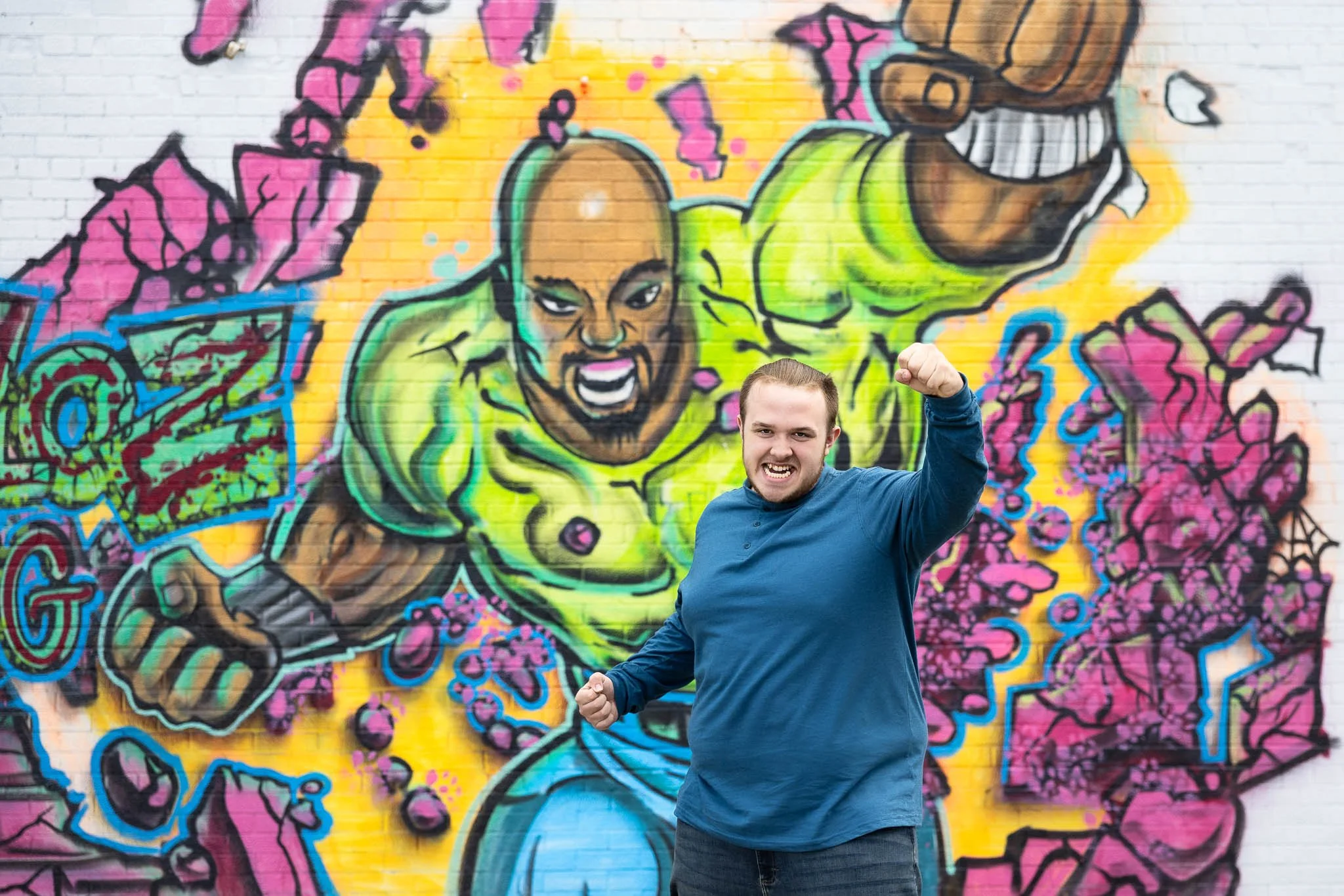 High school senior poses in front of a mural during his Davison, MI senior portrait session.