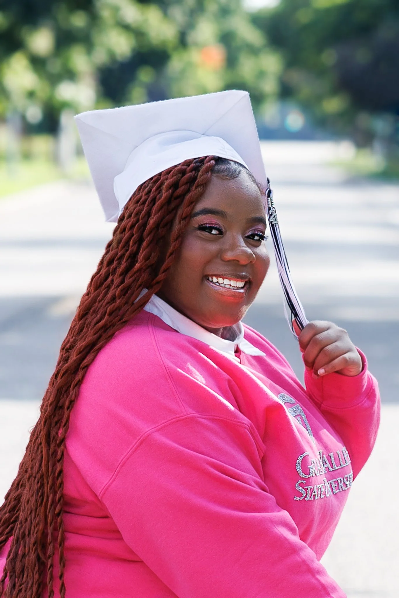 Class of 2024 graduate posing in her cap and tassel near the Flint Cultural Center during her senior portrait session.