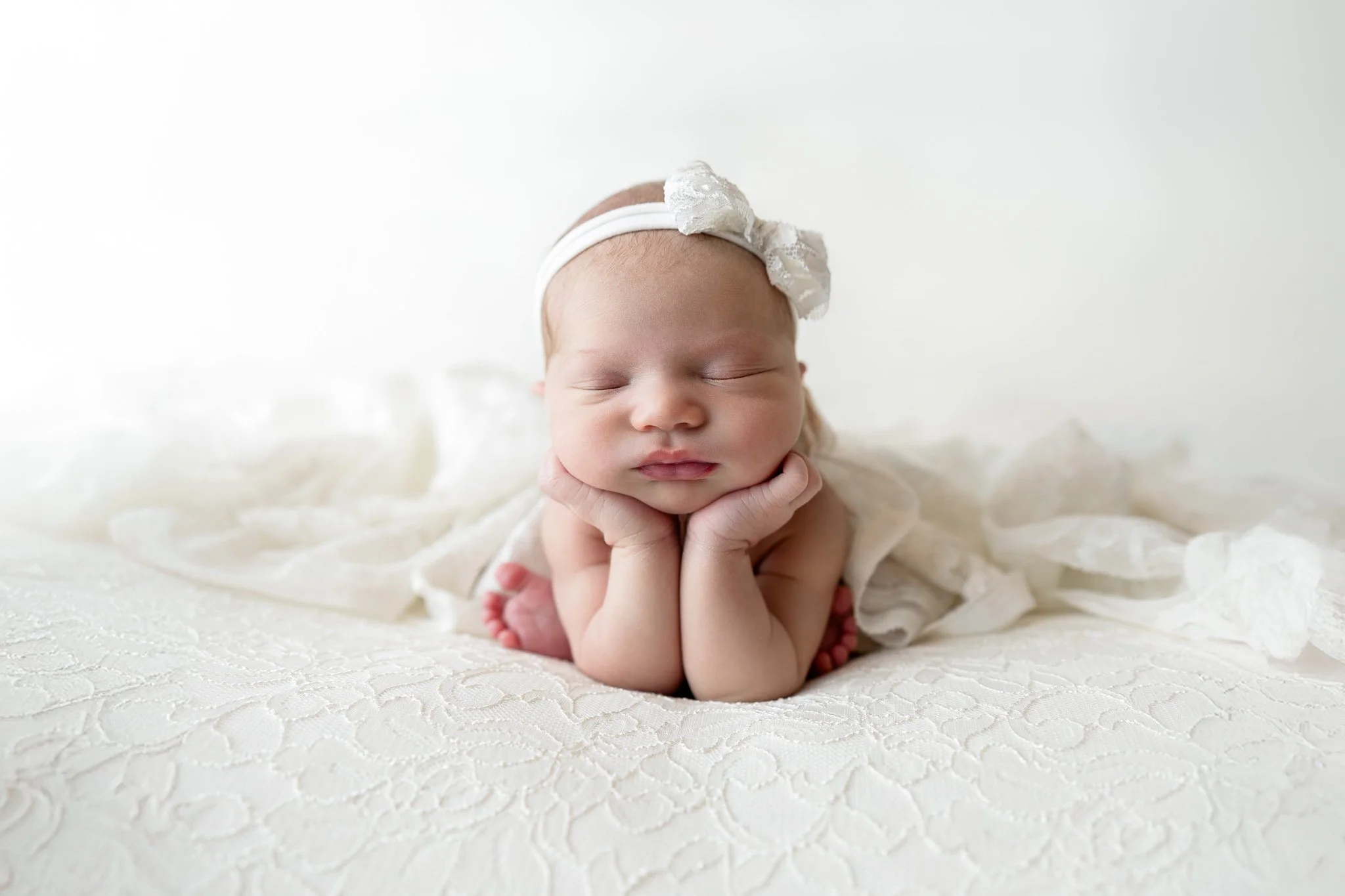 Baby girl in cream lace is in froggy pose during her studio newborn session in Davison, Michigan.