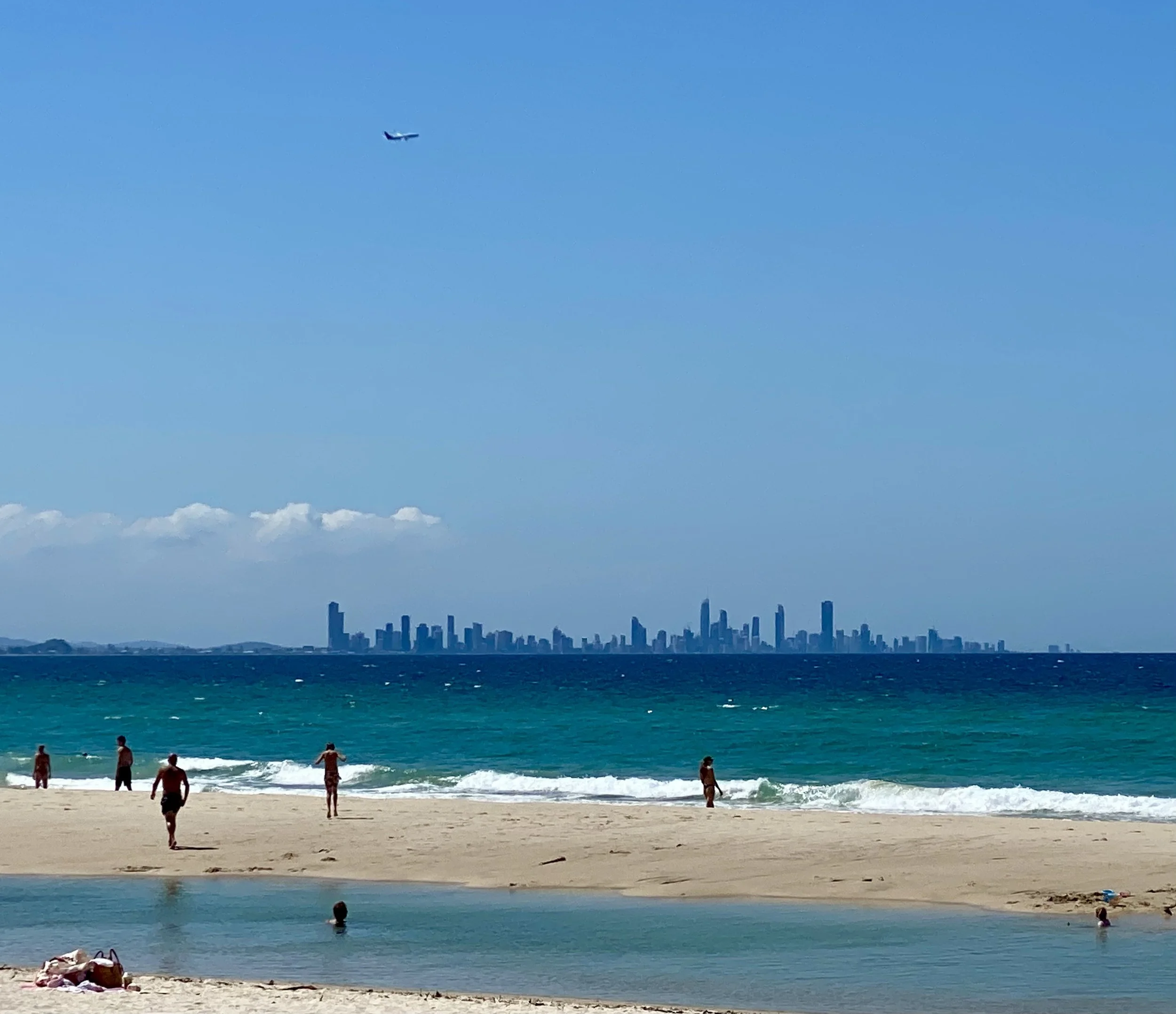Coolangatta beach with Gold Coast in background and plane flying overhead