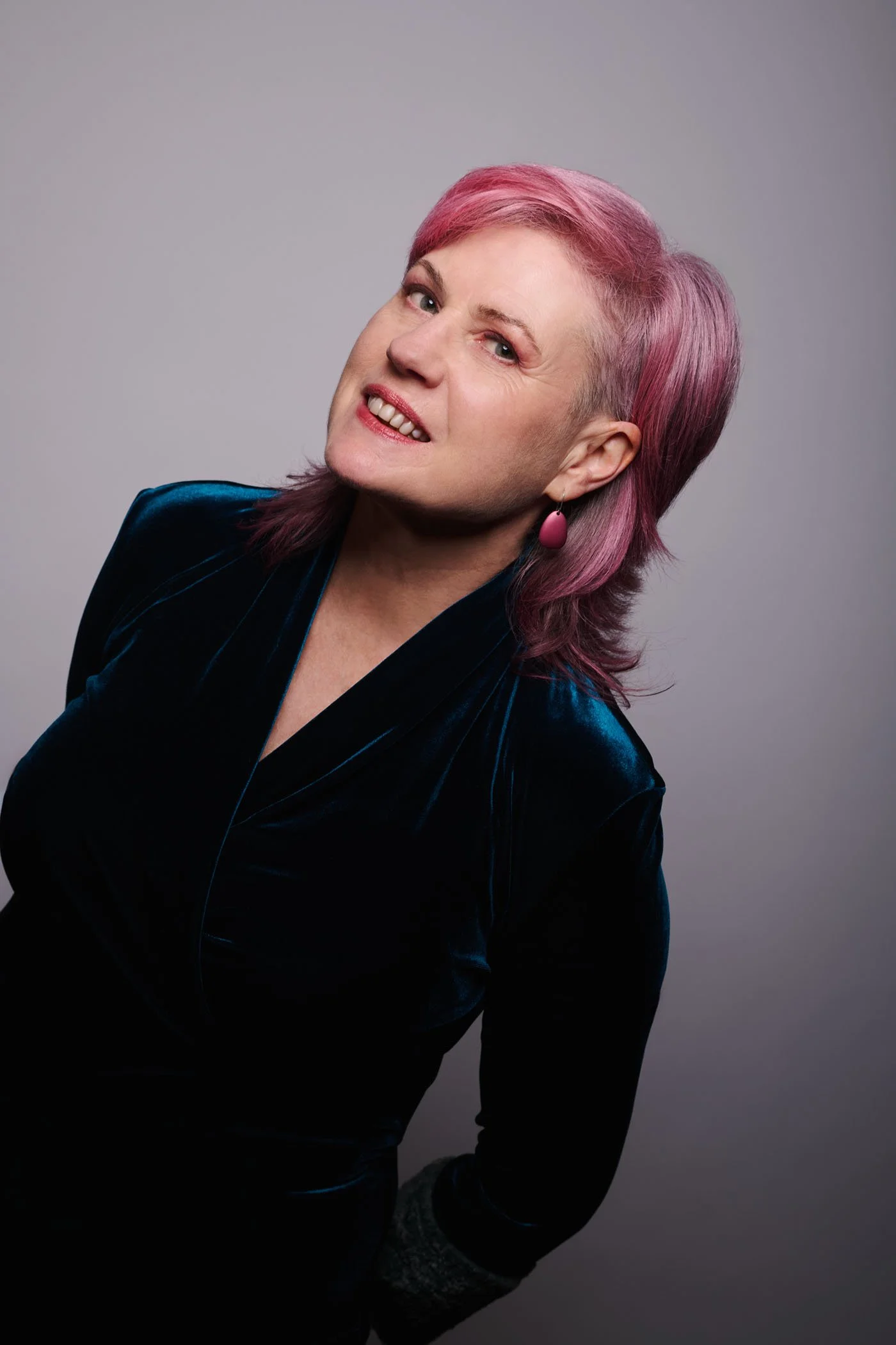 Donna in a deep blue velvet dress, leaning into frame on an angle