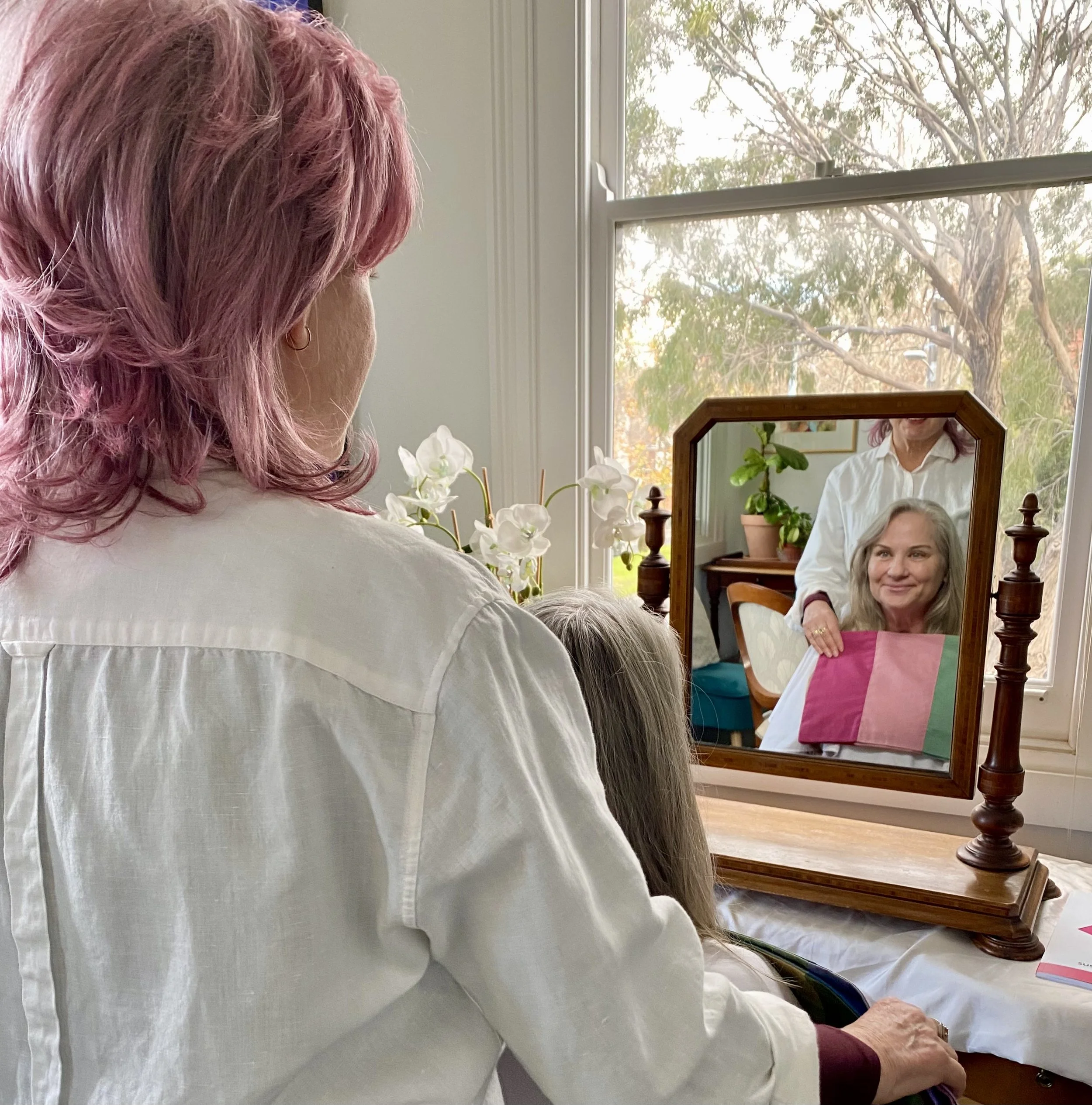 Donna's back s she does a colour analysis with a client reflected in the mirror