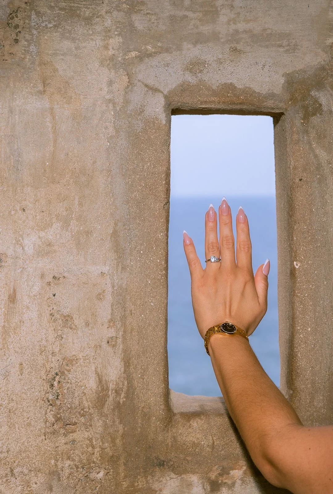 A woman shows her engagement ring against the backdrop of Old San Juan