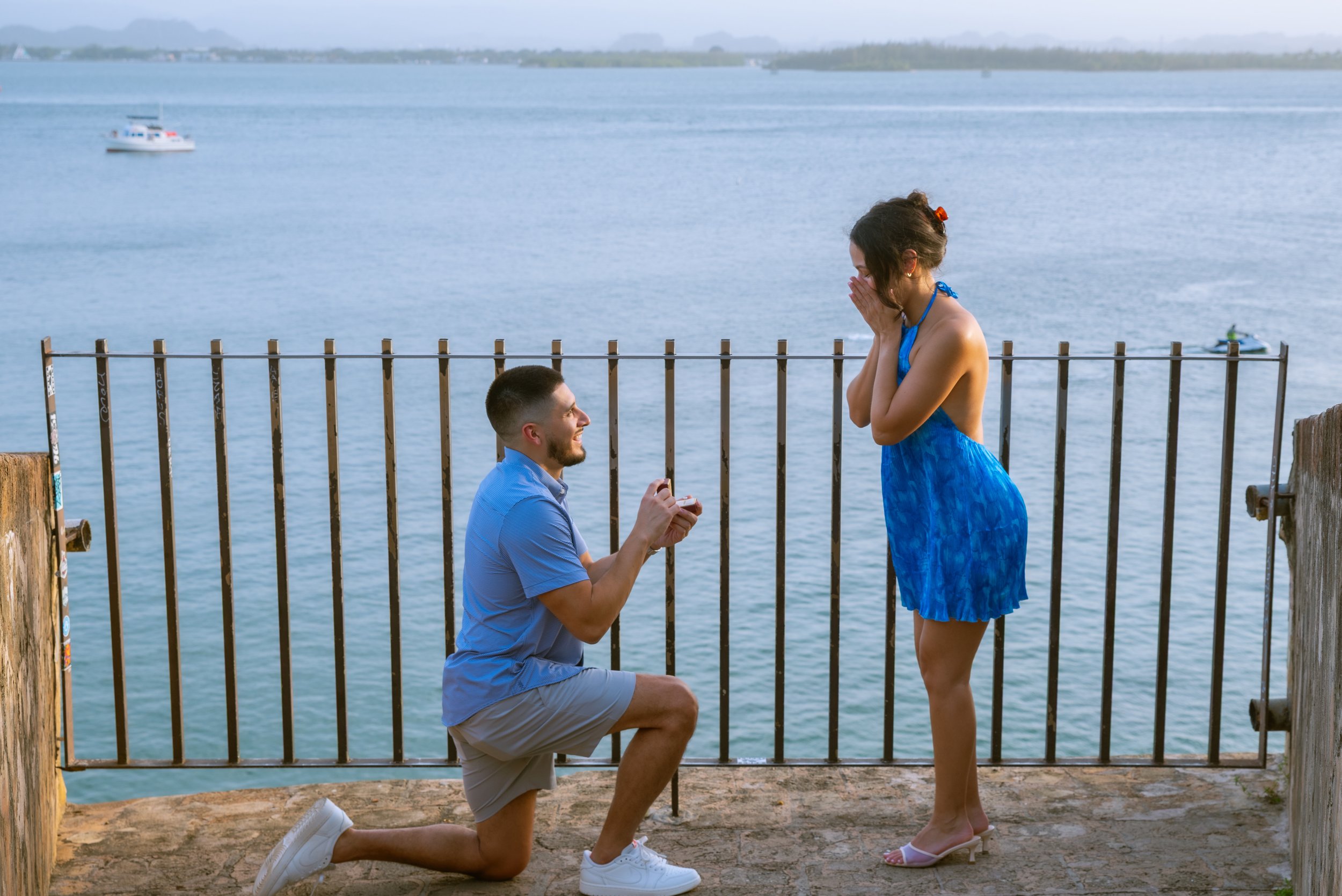 A young man kneels in front of his bride-to-be as she is surprised in Old San Juan