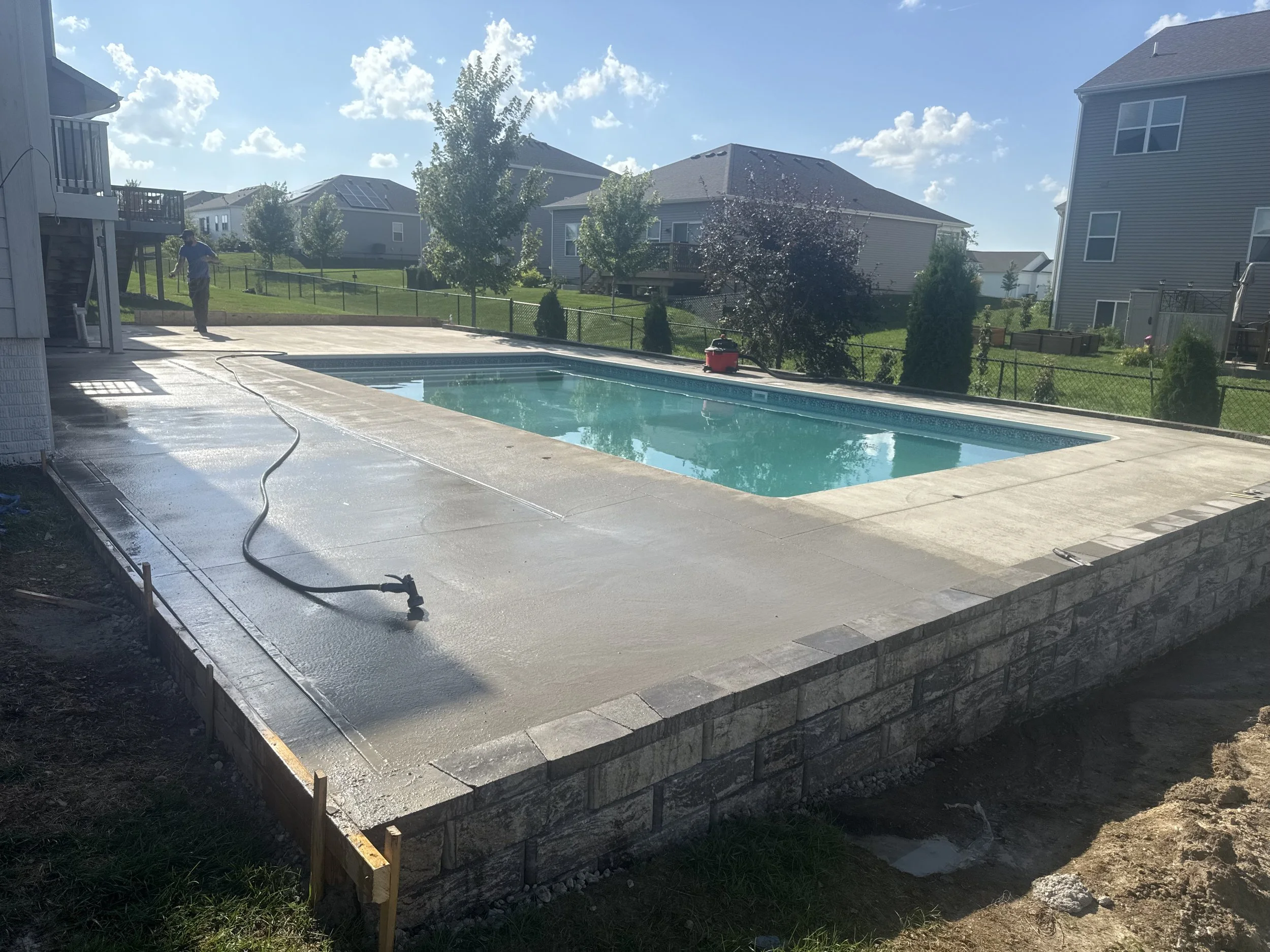 Elevated concrete pool deck pour with an integrated structural block retaining wall in Central Iowa.