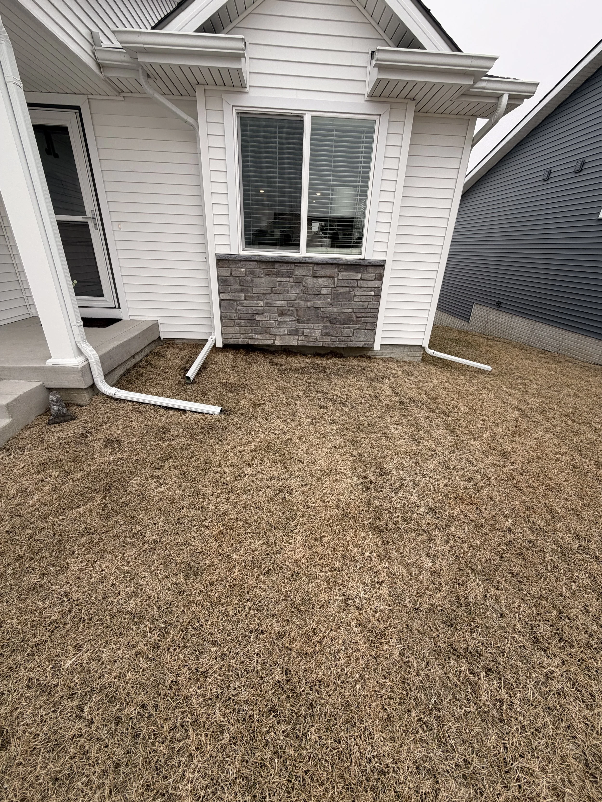 Completed site finish work in Altoona, featuring downspout routing, final grading, and erosion control straw matting.